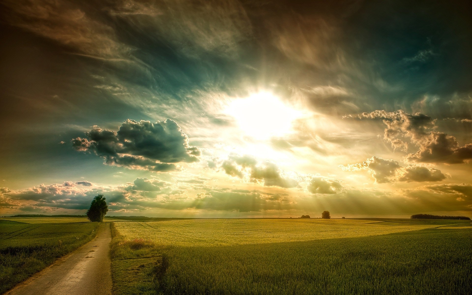 Sunlight shining through clouds over a field HD Wallpaper