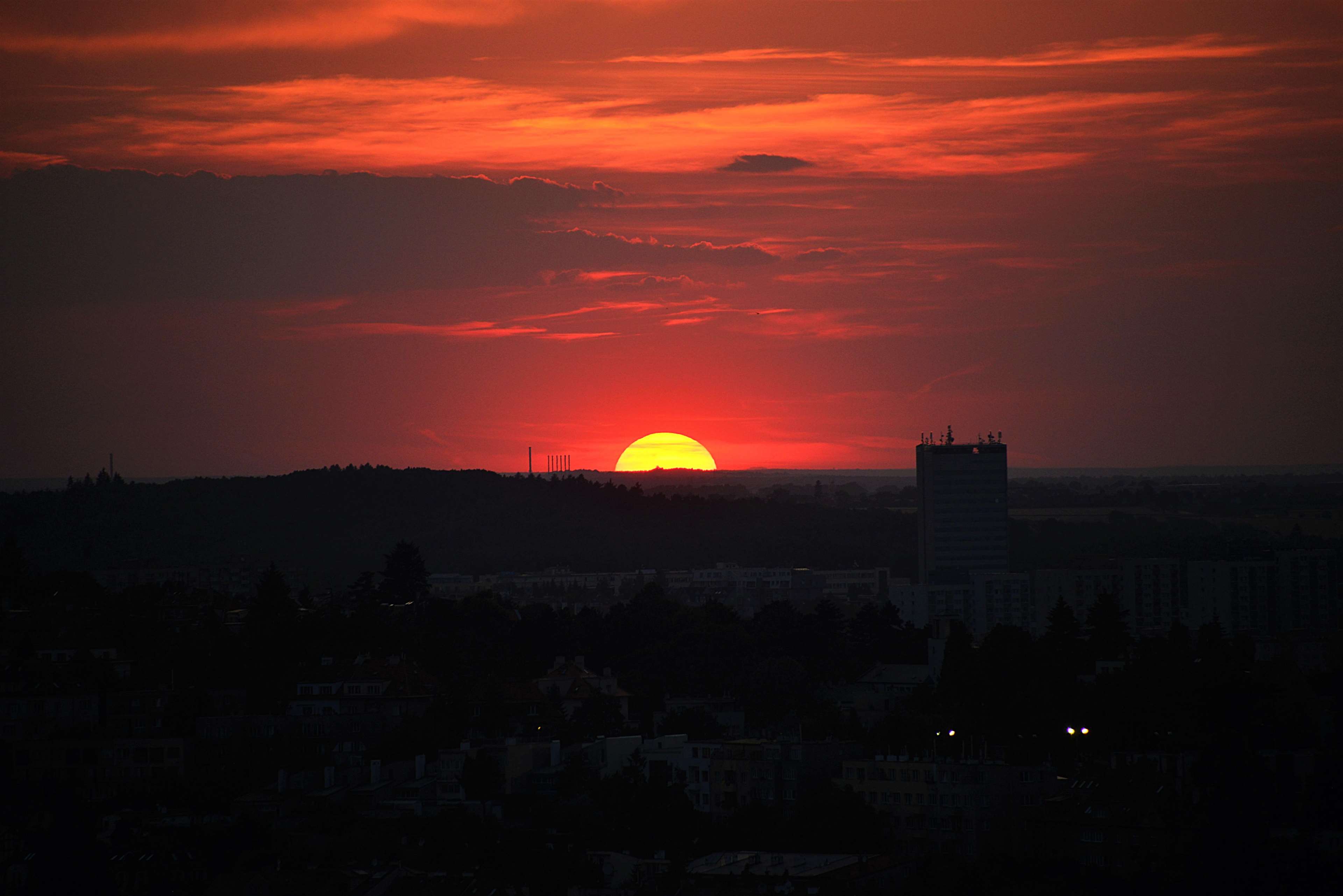 Sunset over a city skyline with a tall building HD Wallpaper