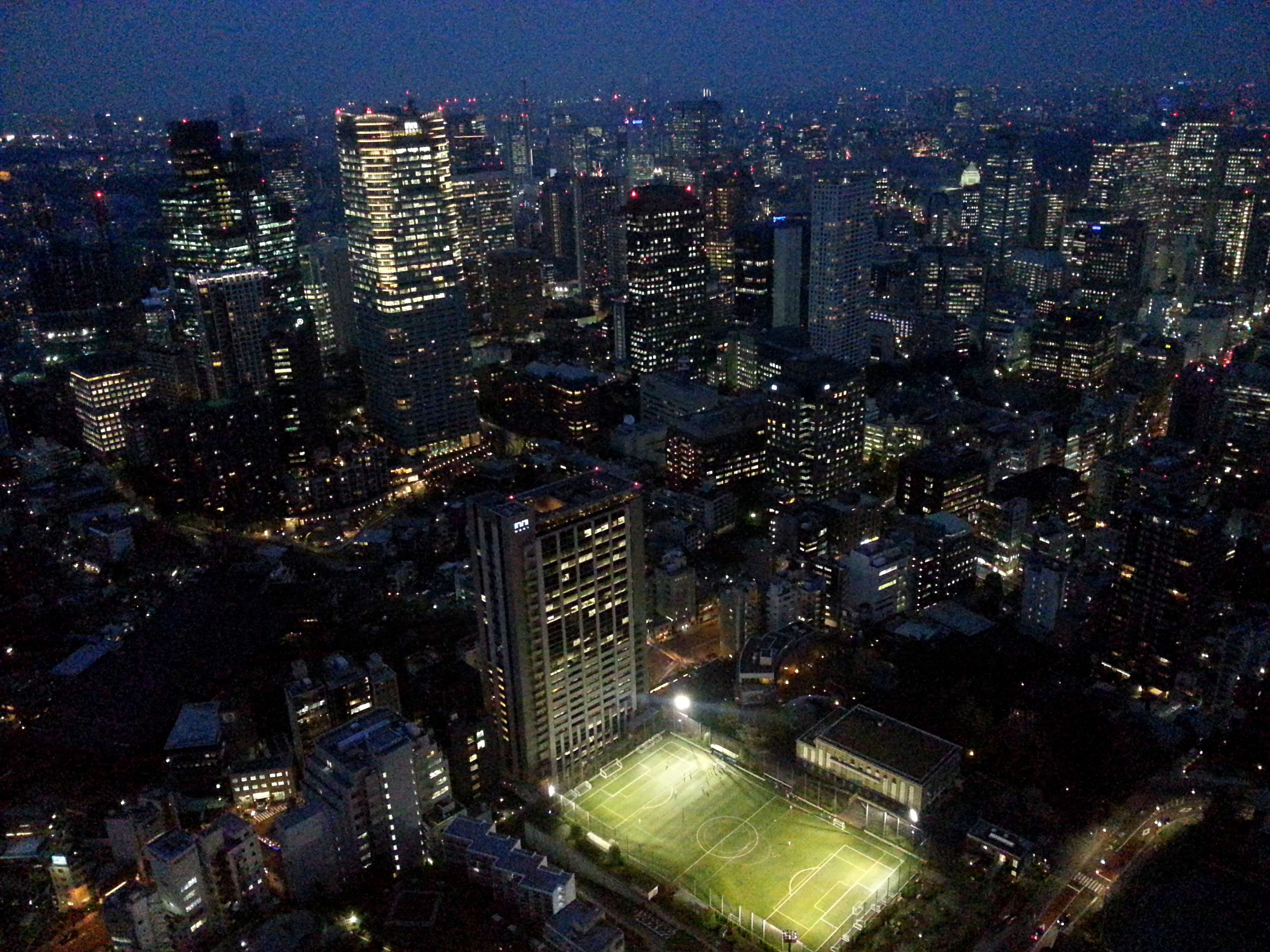 Night view of Tokyo cityscape with illuminated buildings and soccer field HD Wallpaper