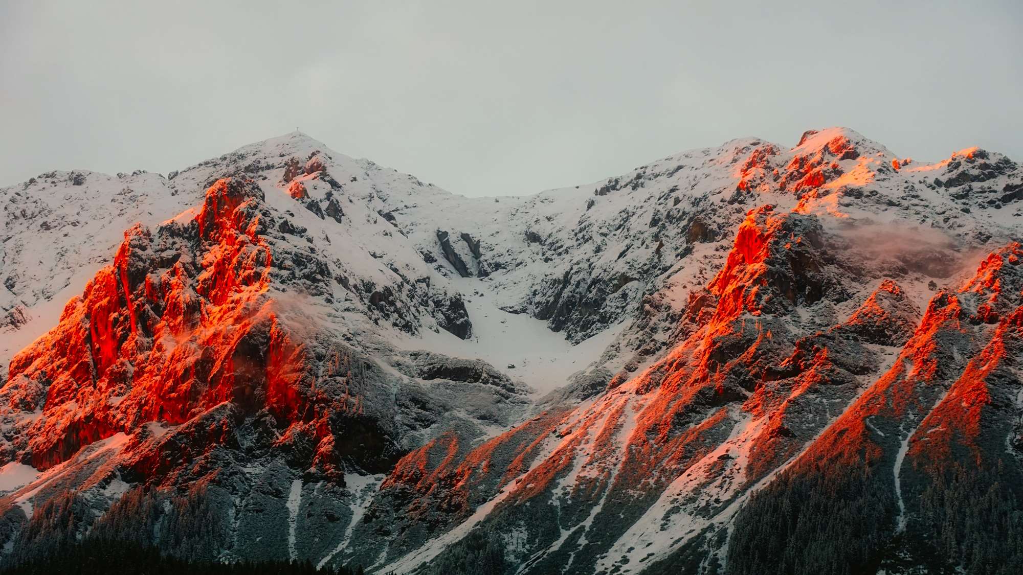 Snowy mountains illuminated by orange sunset light HD Wallpaper