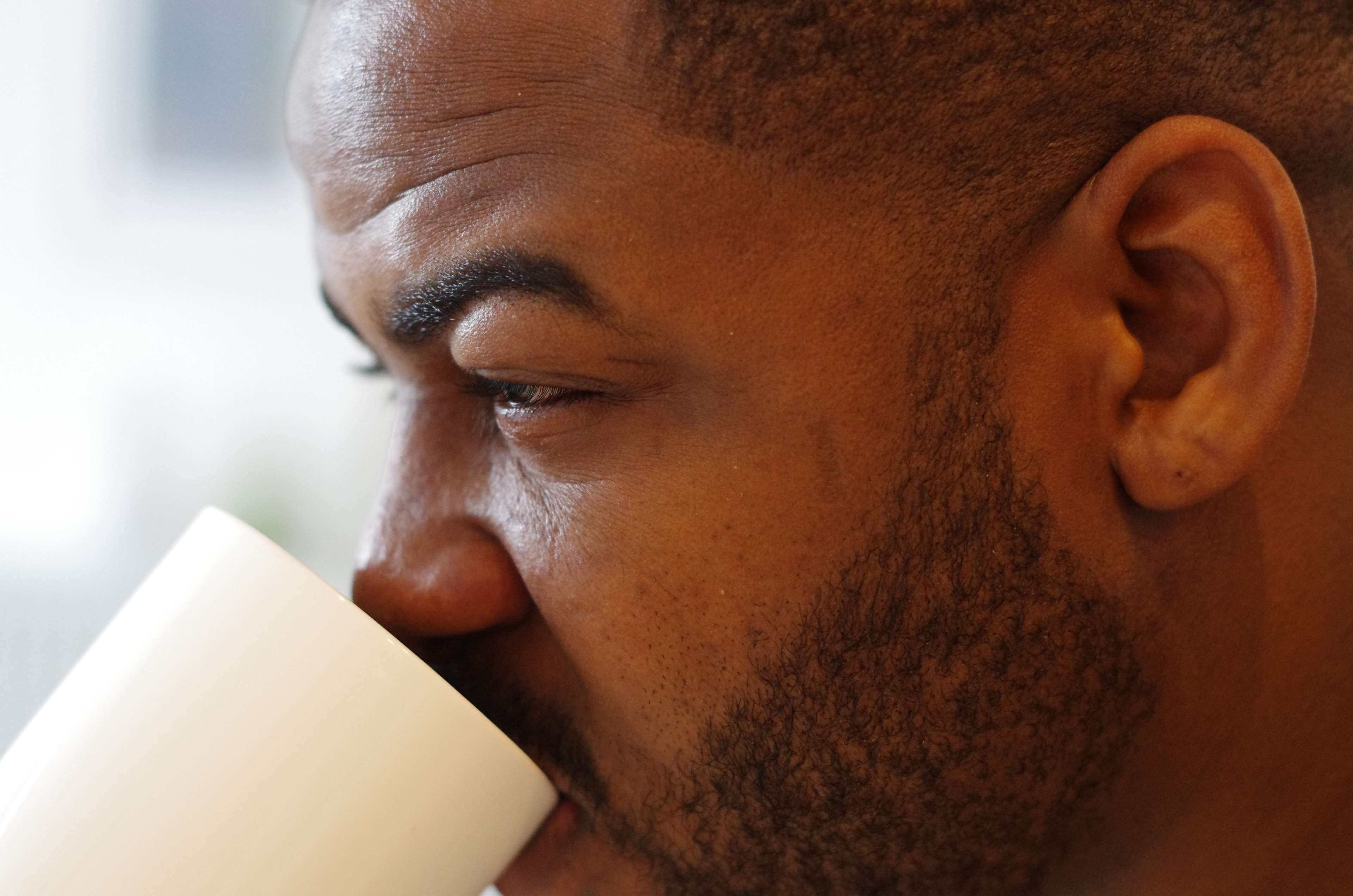Black man drinking from a white coffee cup HD Wallpaper