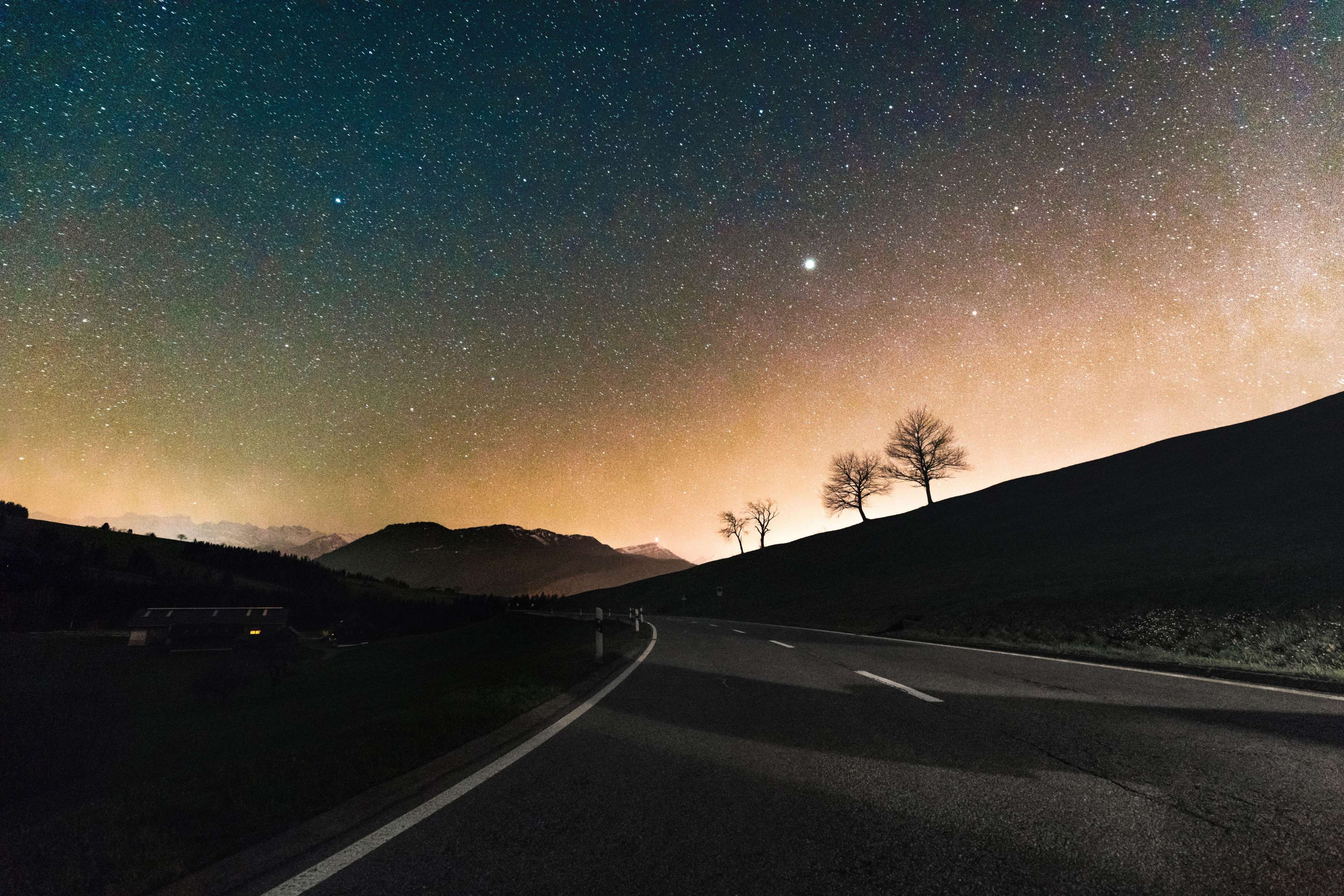 Road under starry sky with trees and mountains HD Wallpaper