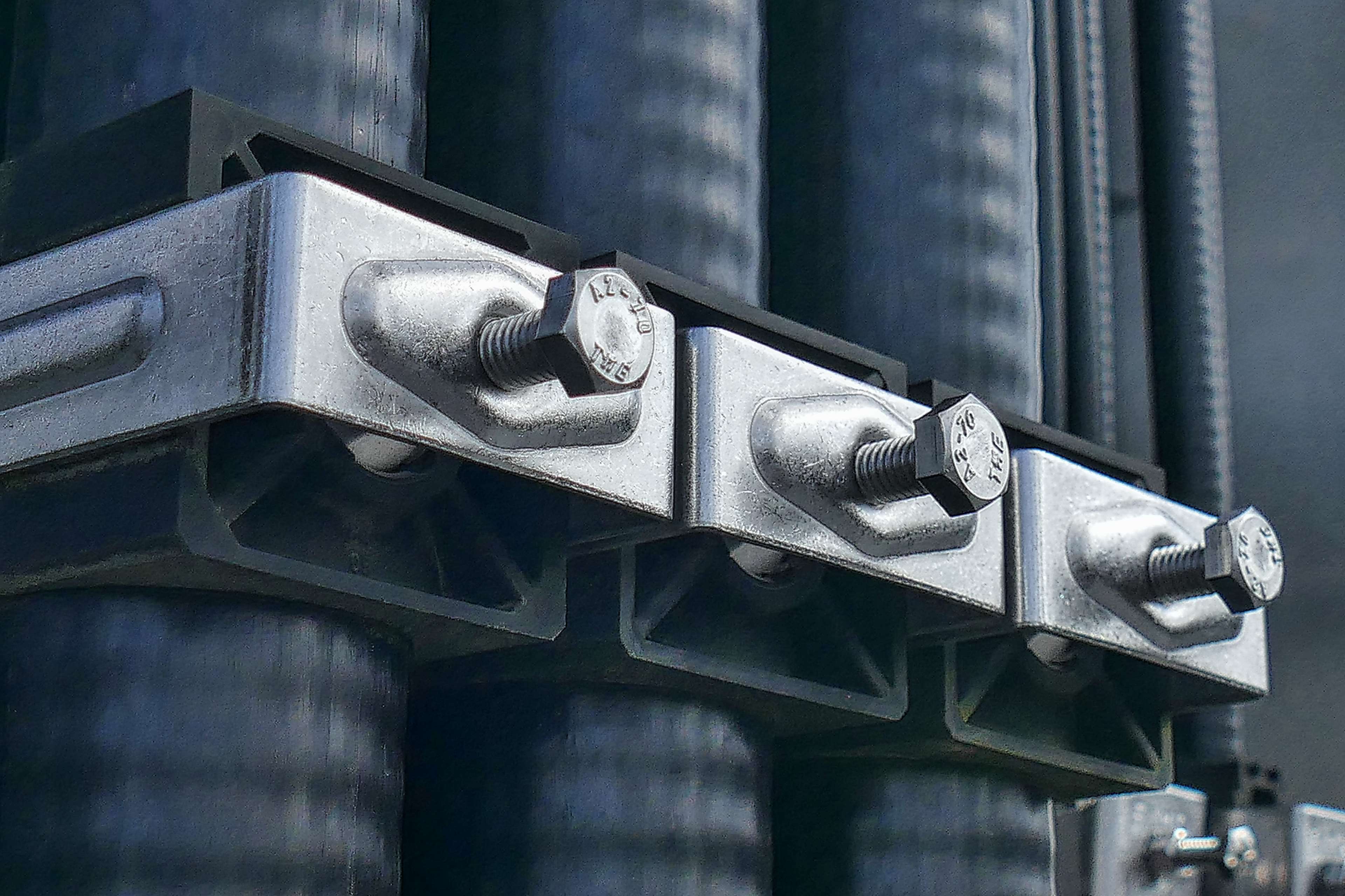 Industrial metal clamps holding pipes with bolts HD Wallpaper