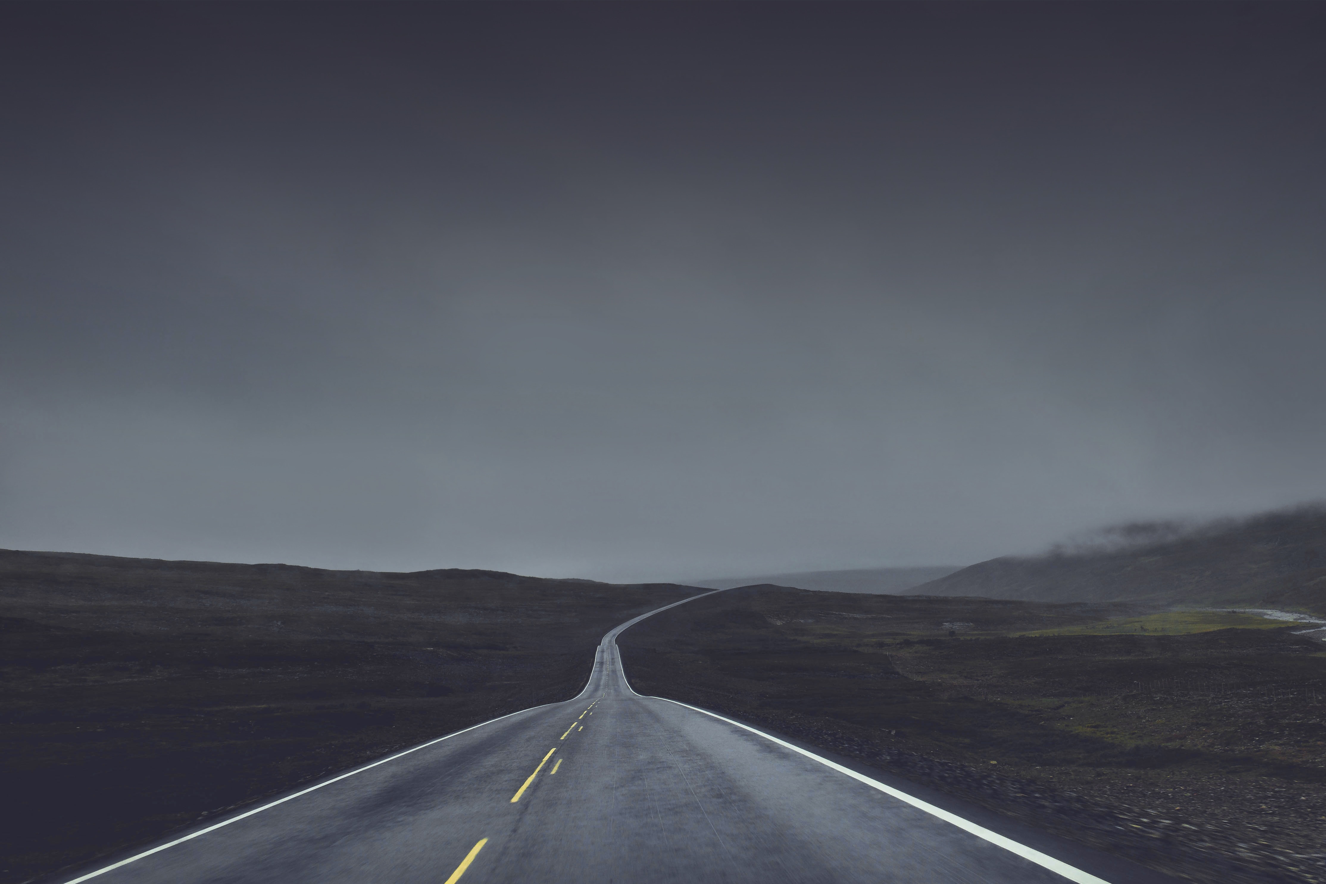 Empty highway stretching into a foggy landscape HD Wallpaper