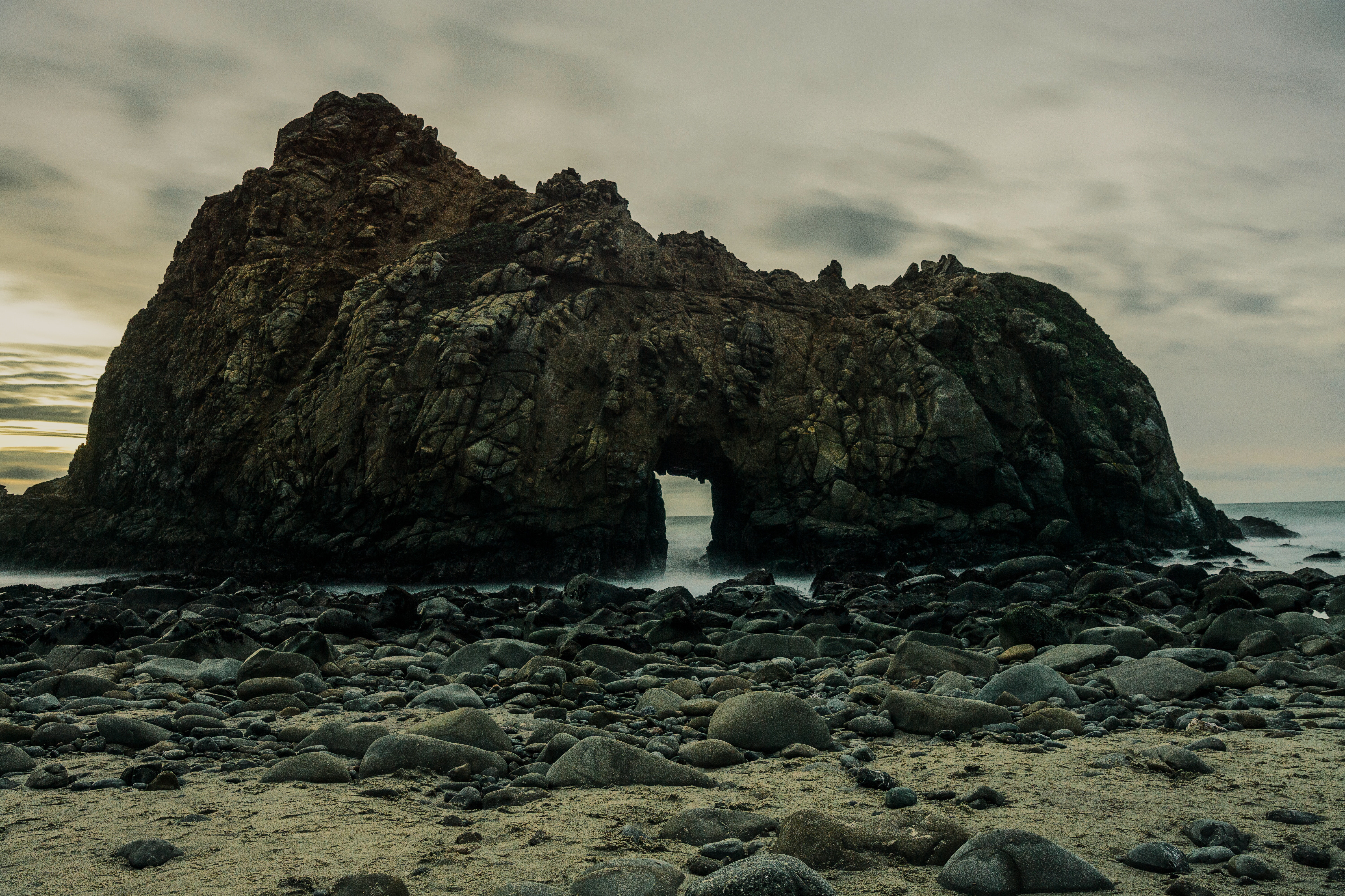 Rock arch tunnel on a rocky beach with ocean waves HD Wallpaper