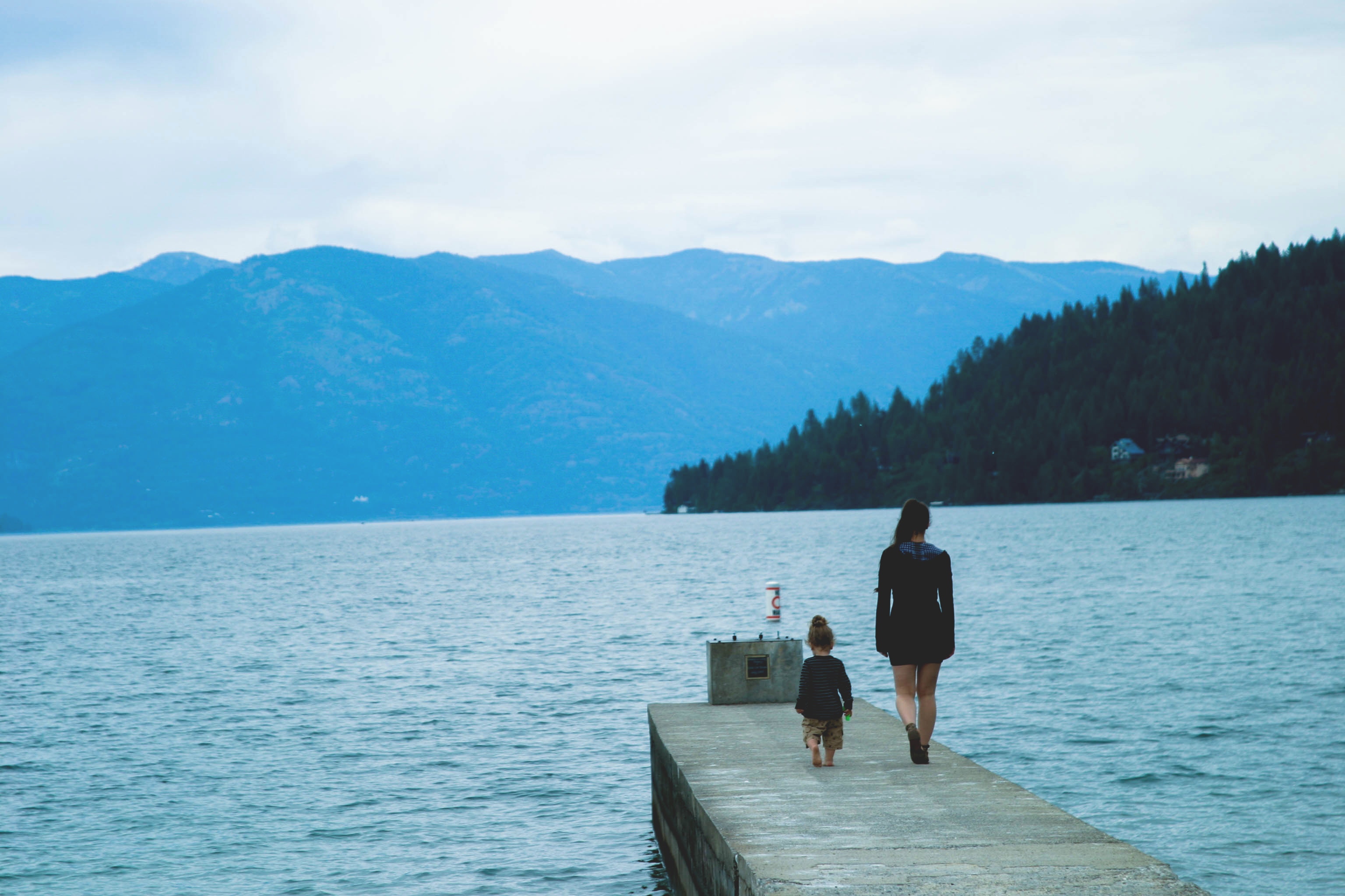 Mother and child walk on a dock by a lake HD Wallpaper