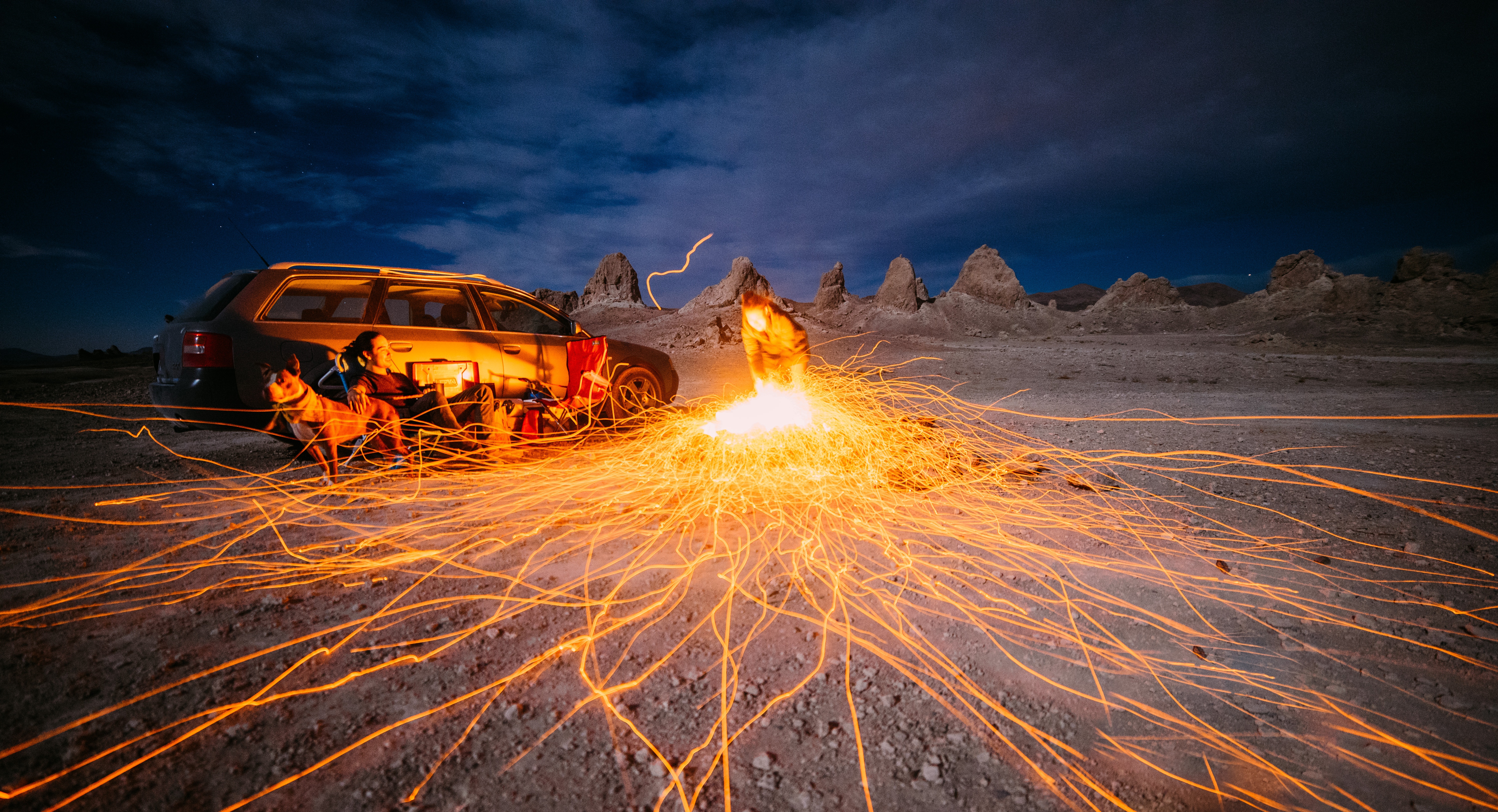 Car and dog at night with sparks in desert HD Wallpaper