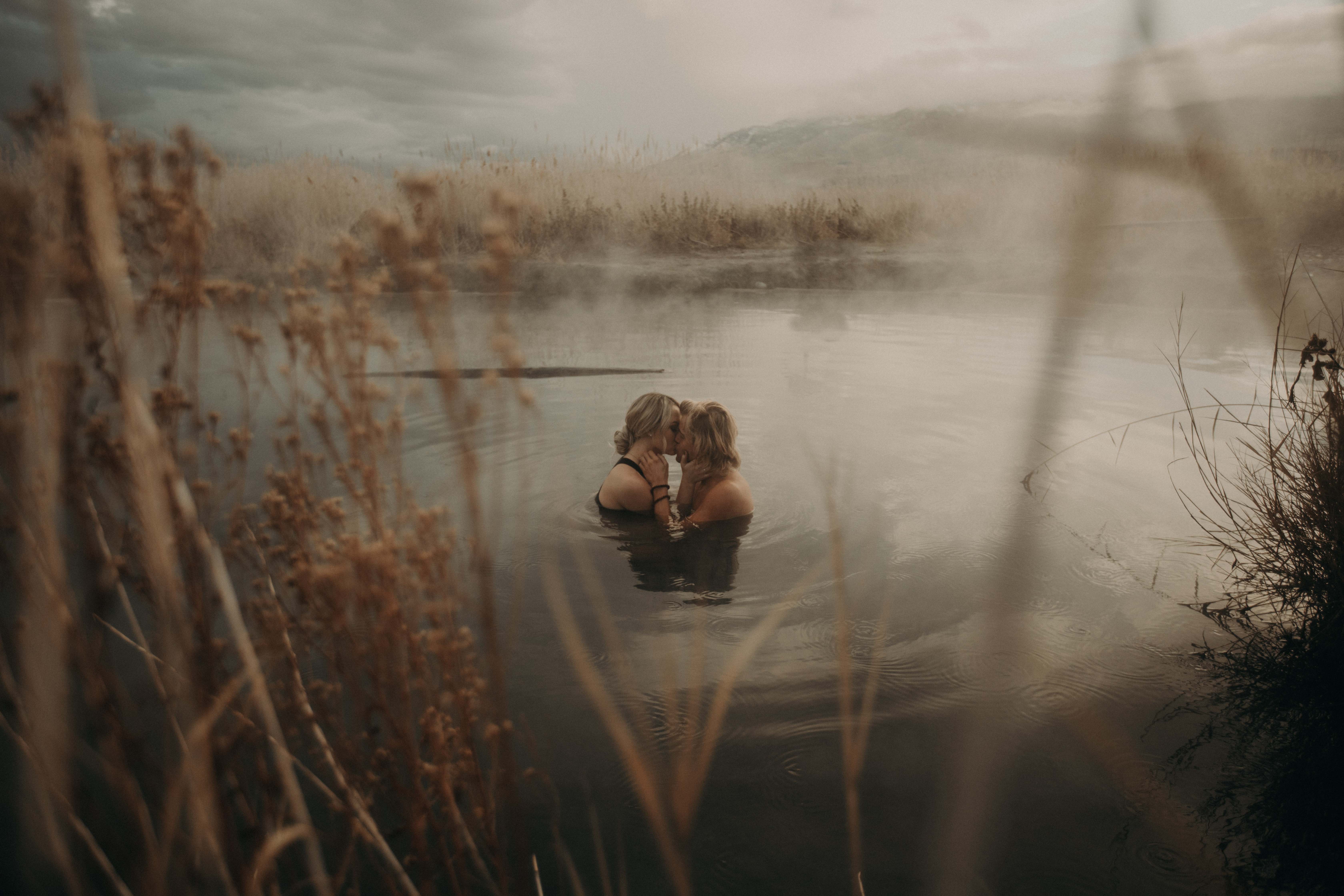Two people kissing in a misty lake with reeds HD Wallpaper