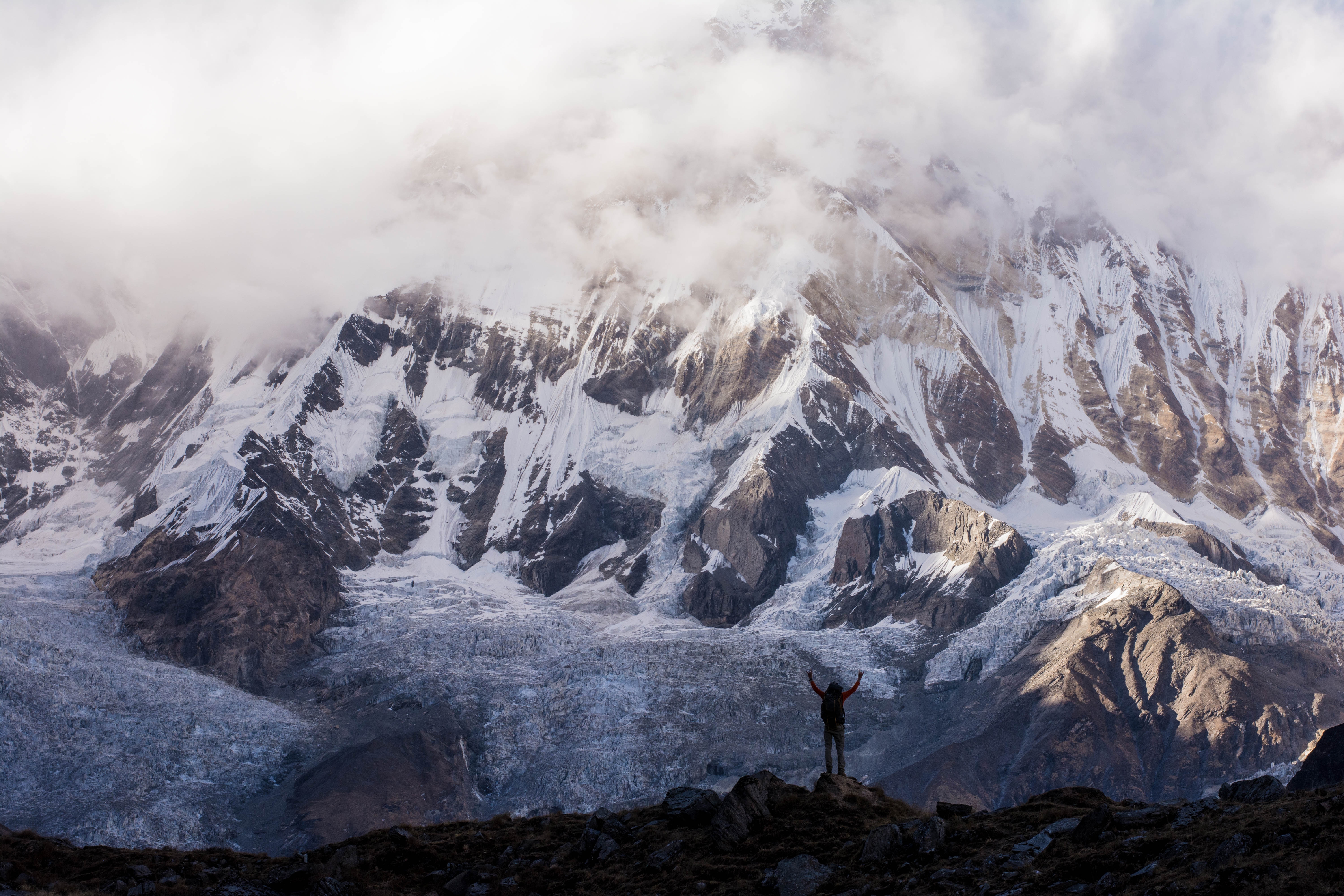 Person hiking in front of a snowy mountain range in Nepal HD Wallpaper