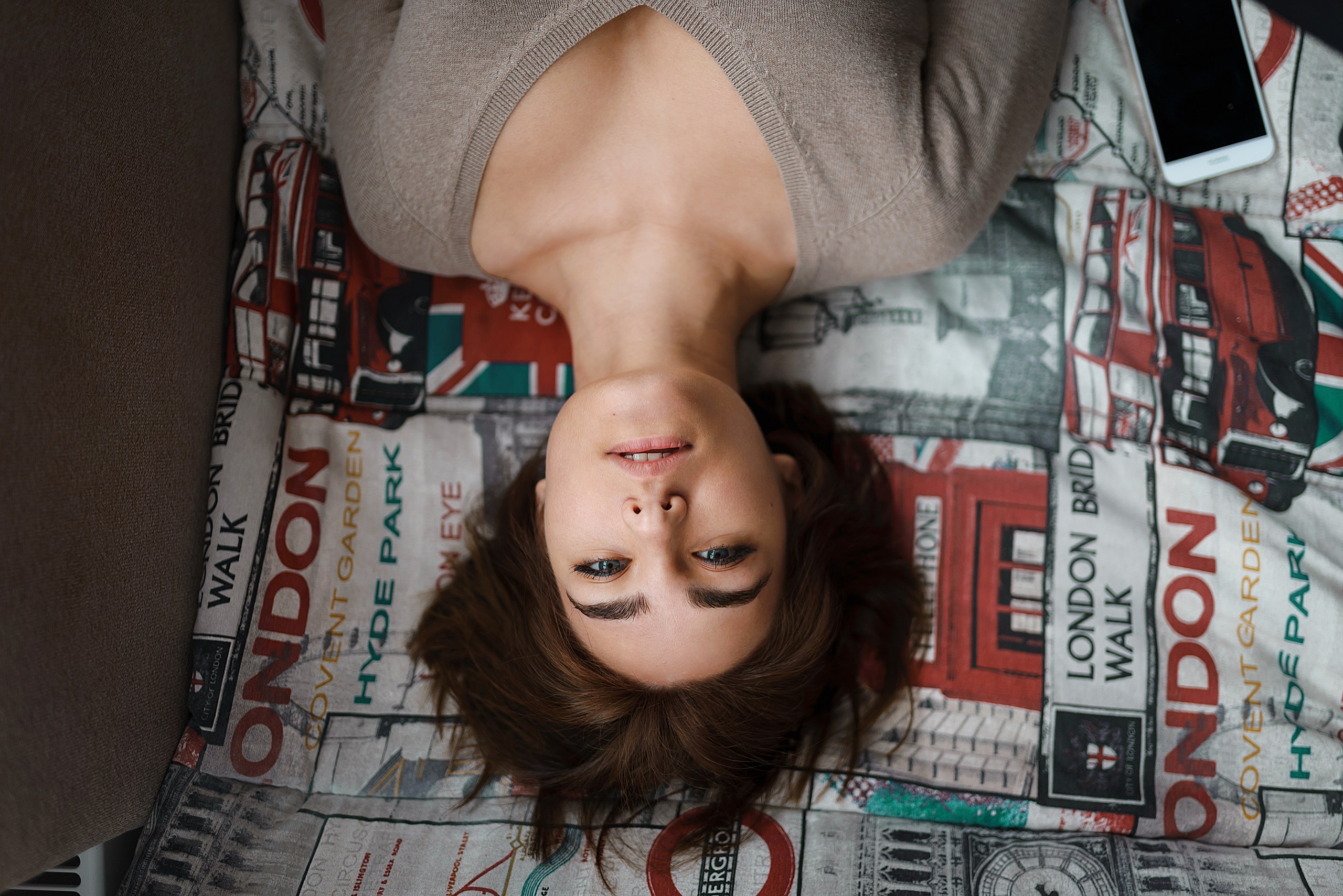 Woman lying on London-themed bedding with phone HD Wallpaper