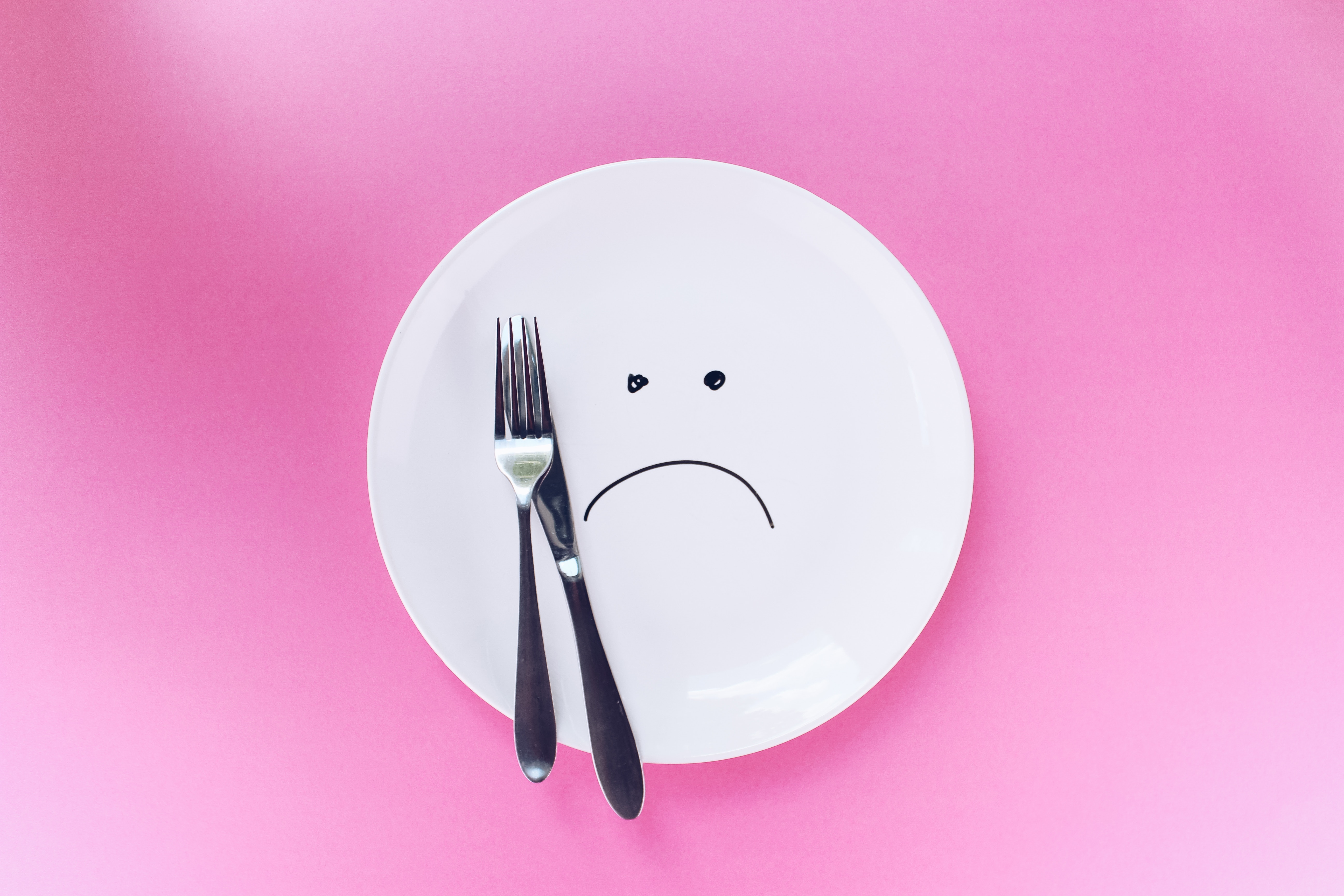 Sad face drawn on a plate with fork and knife HD Wallpaper