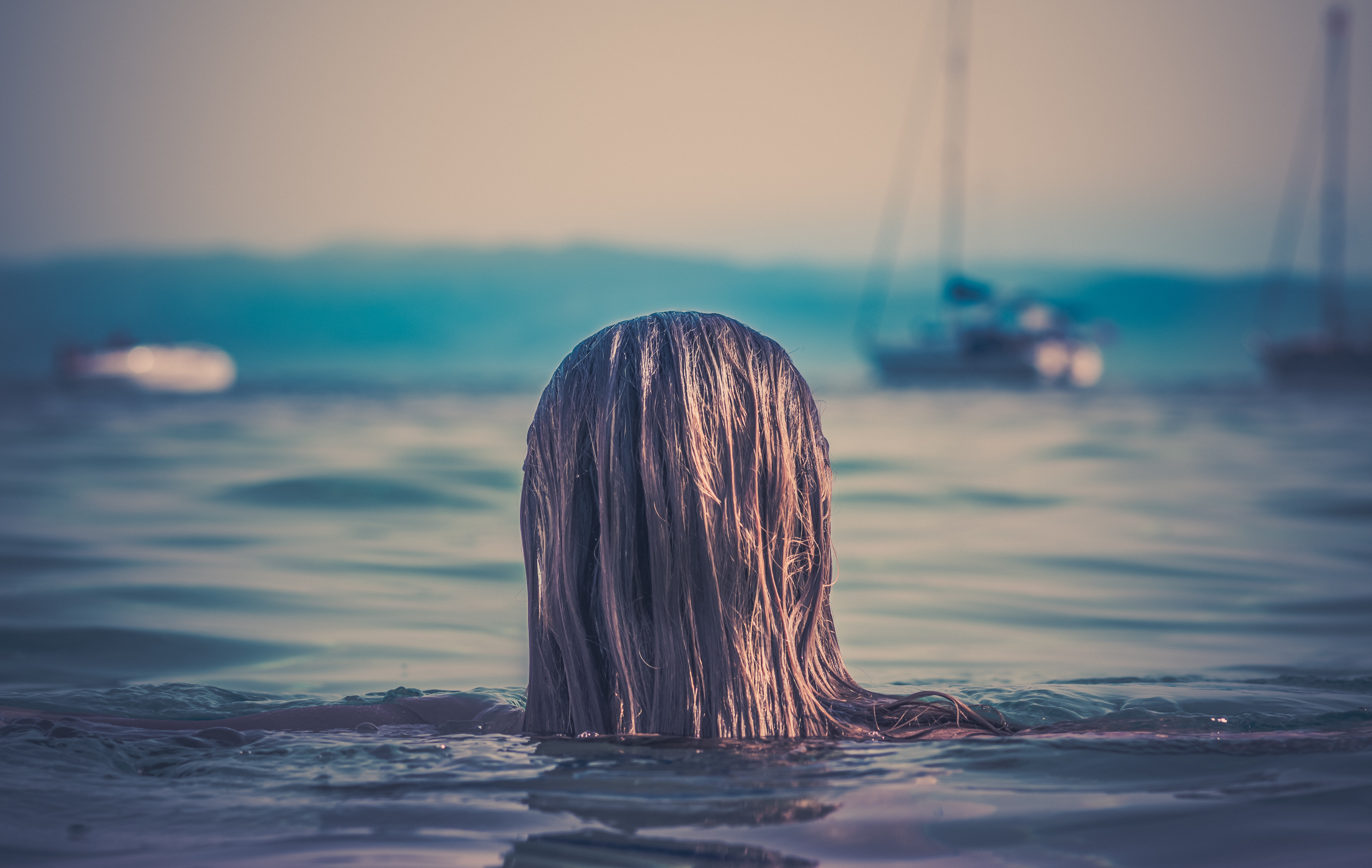 Woman with wet hair swimming in the sea near boats HD Wallpaper