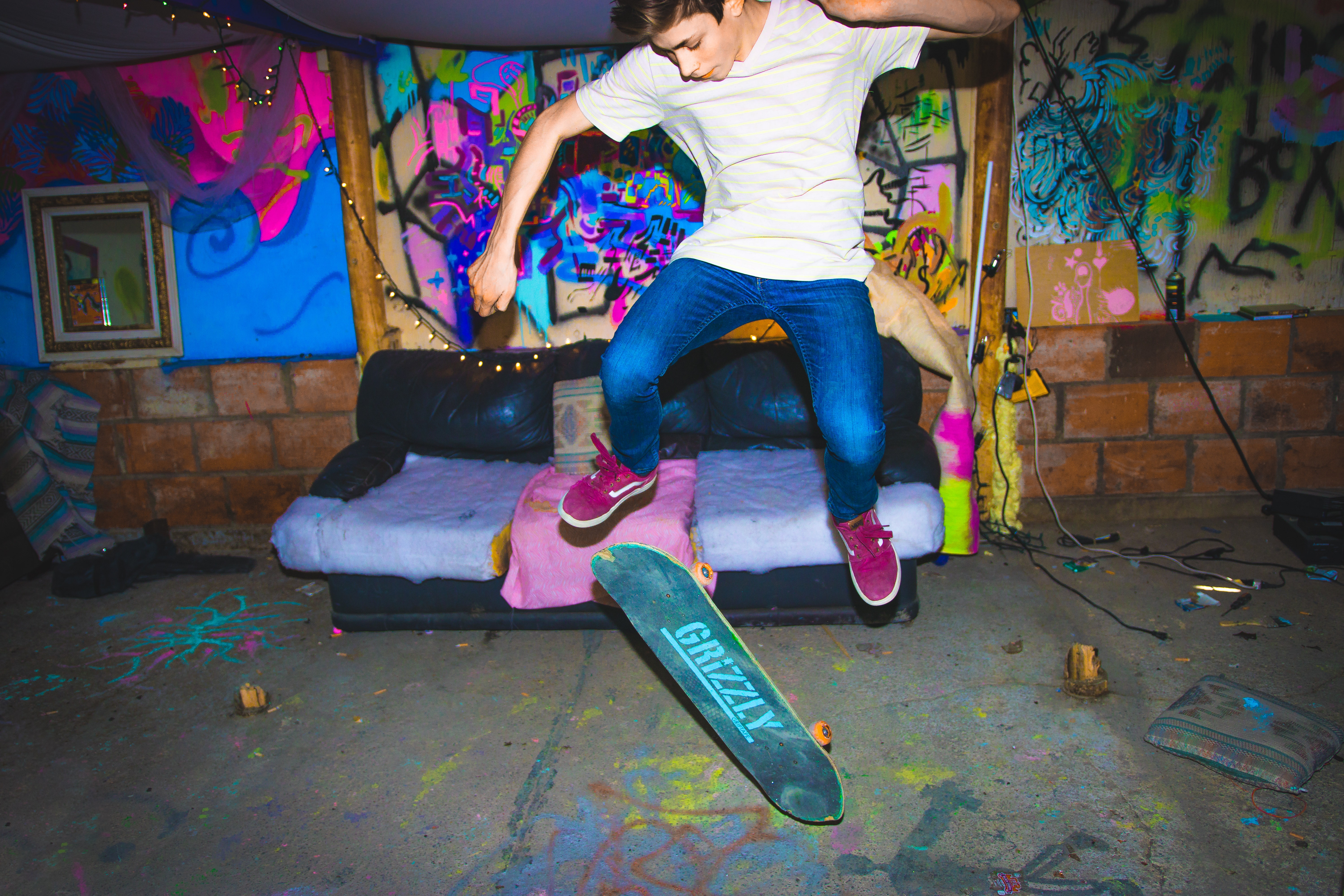Teenage skateboarder jumps with Grizzly skateboard indoors HD Wallpaper