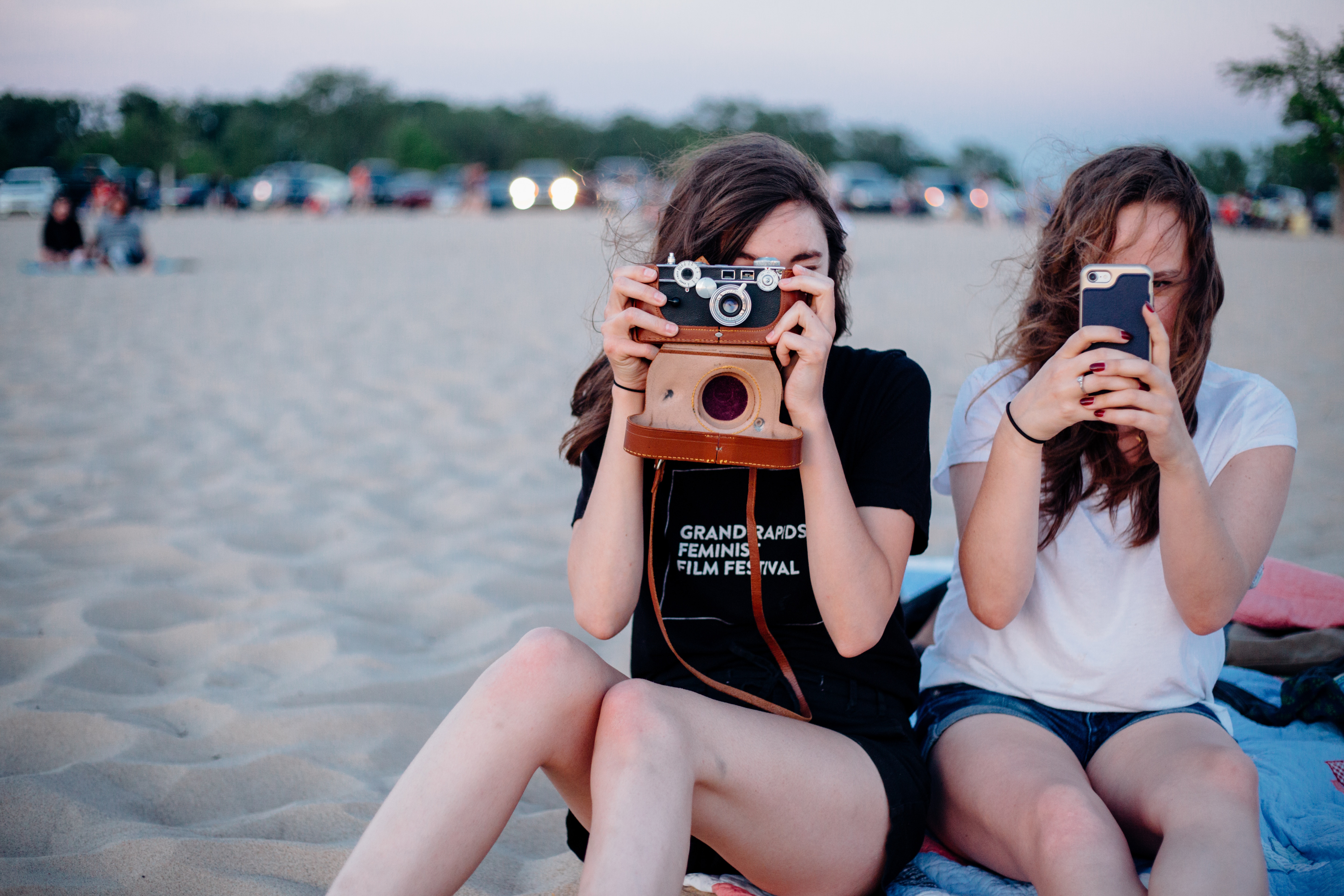 Two women taking photos on the beach HD Wallpaper