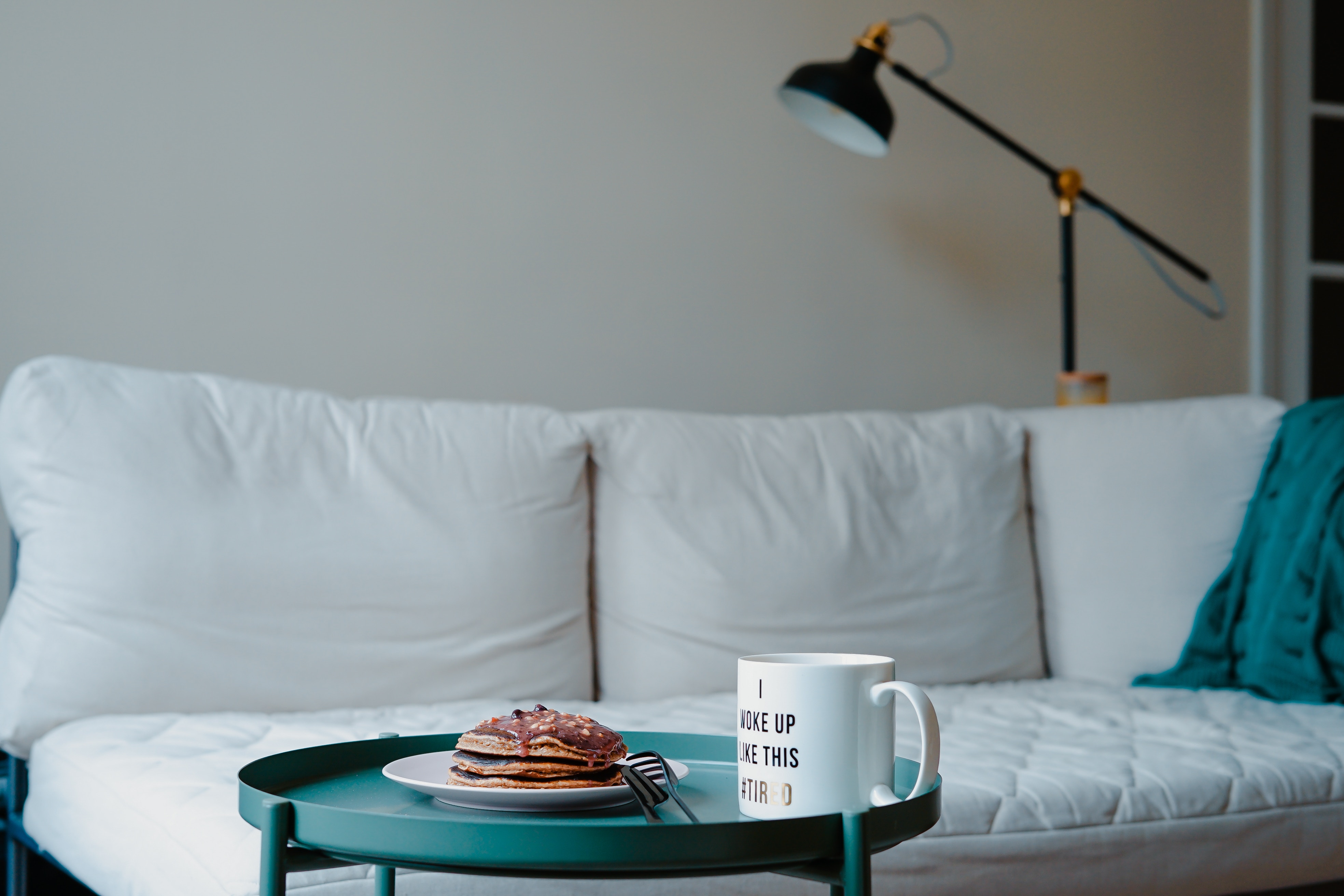 Pancakes and coffee mug on a table in front of a couch HD Wallpaper