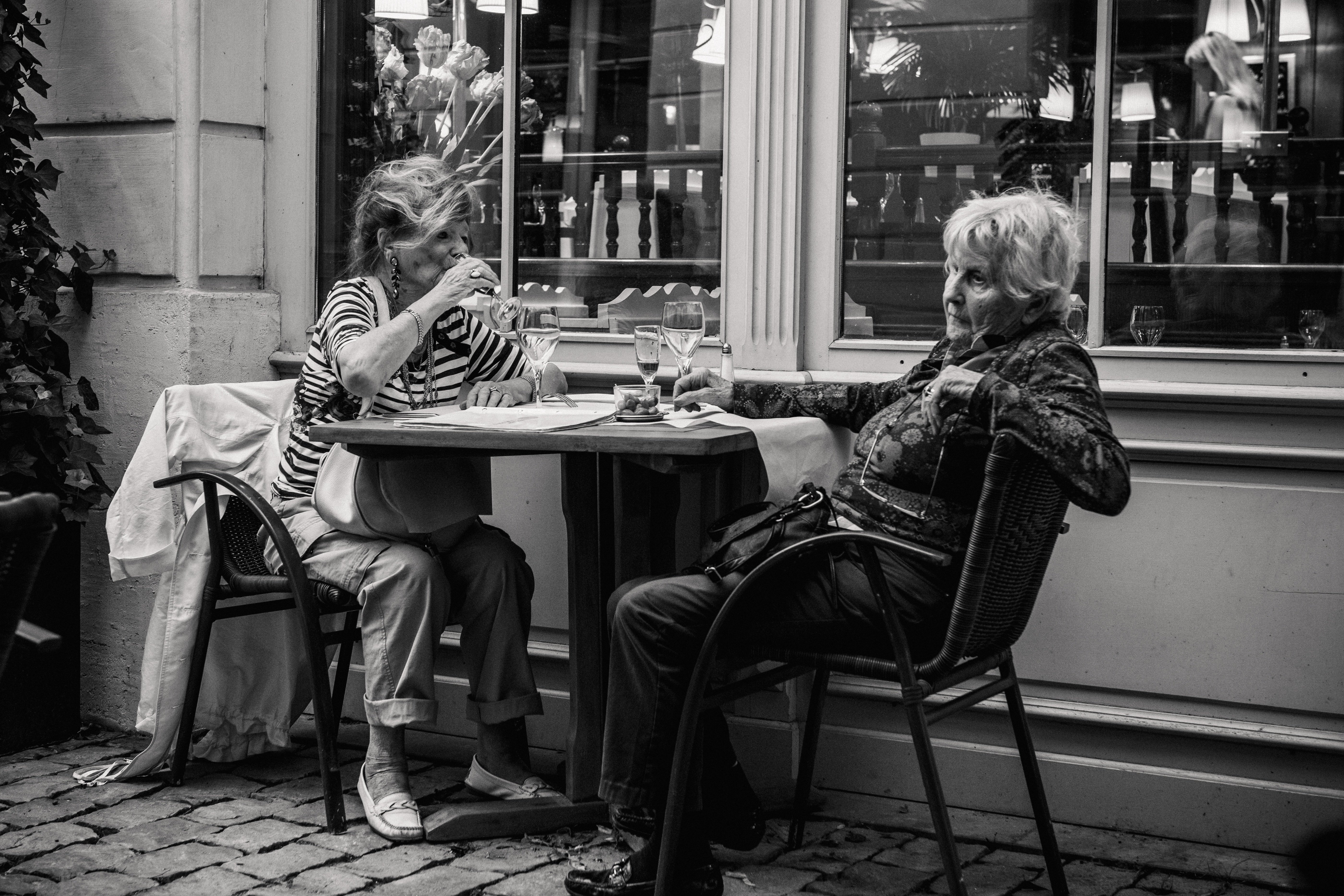 Two women dining at a restaurant table in Paris HD Wallpaper