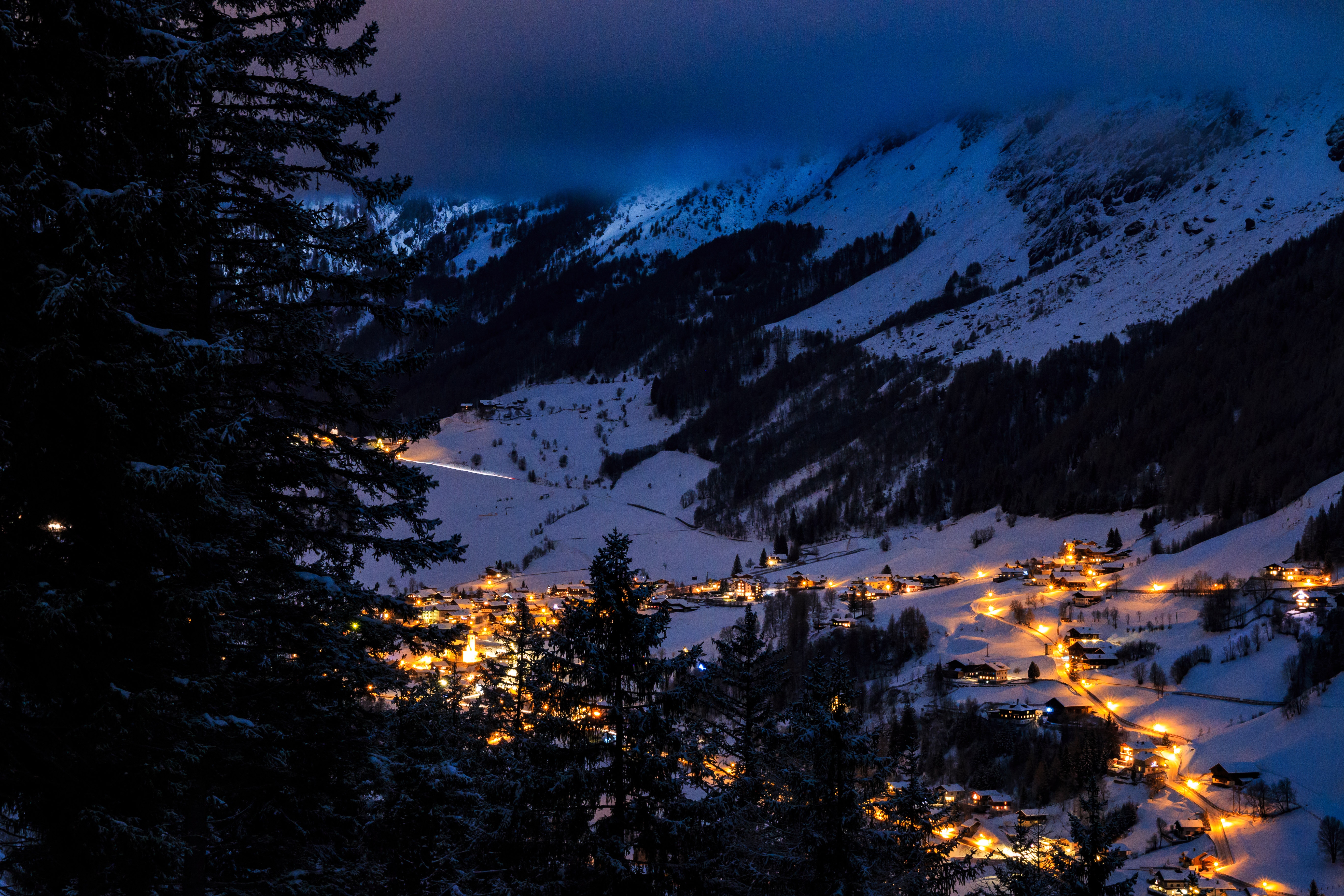 Village lights in a snowy mountain valley at night HD Wallpaper