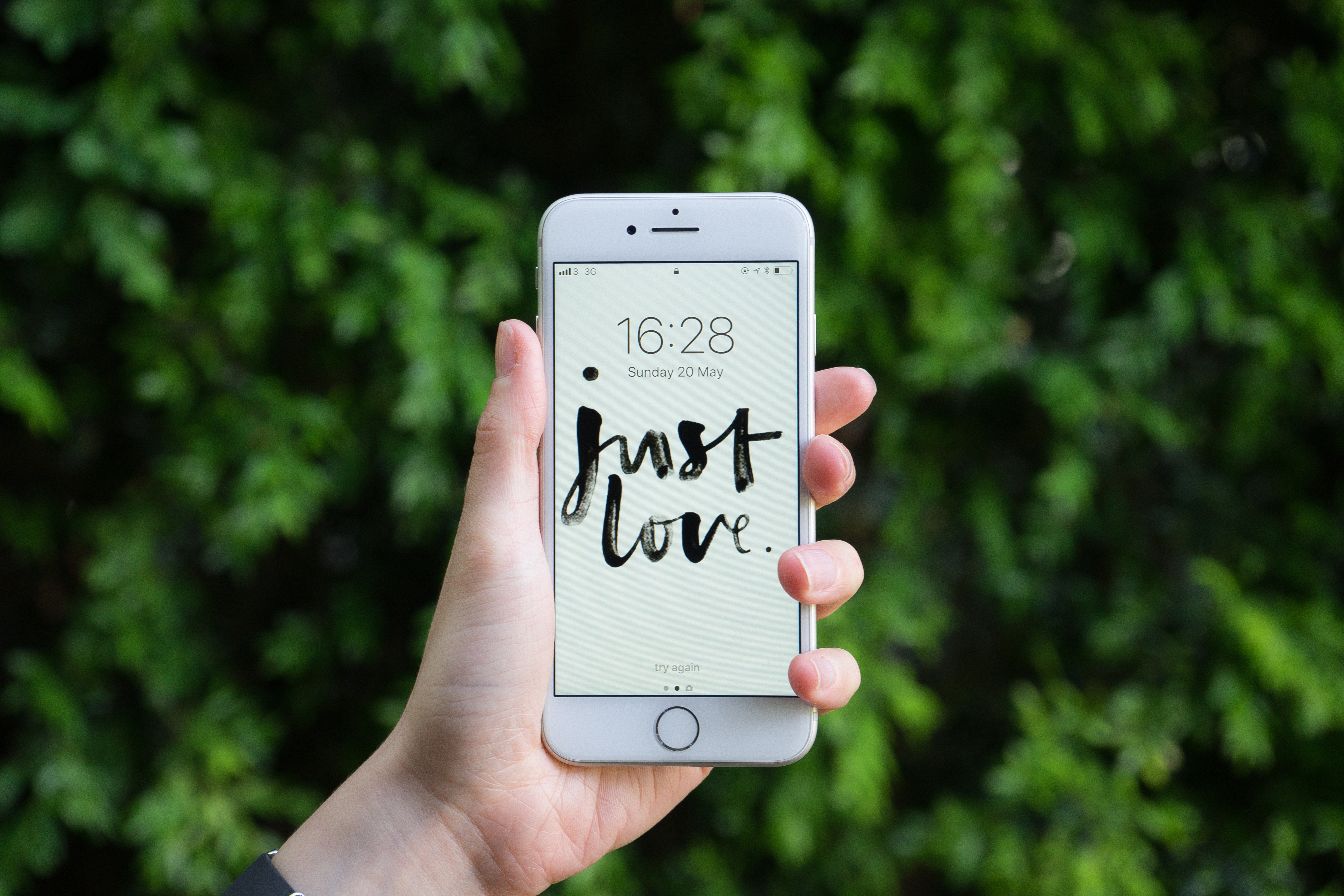 iPhone 7 with "just love" wallpaper held outdoors HD Wallpaper