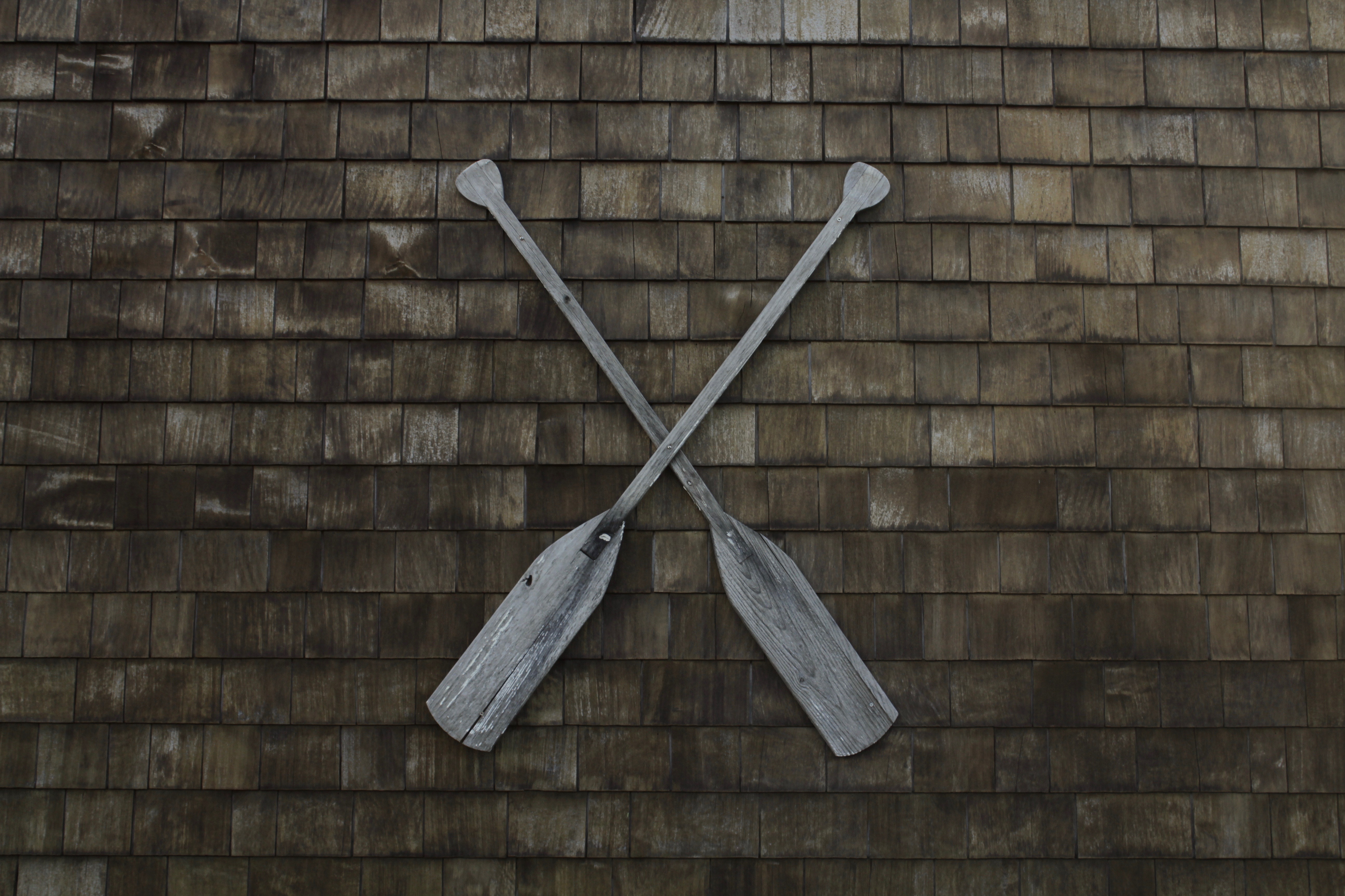 Two wooden oars crossed on a shingled wall HD Wallpaper