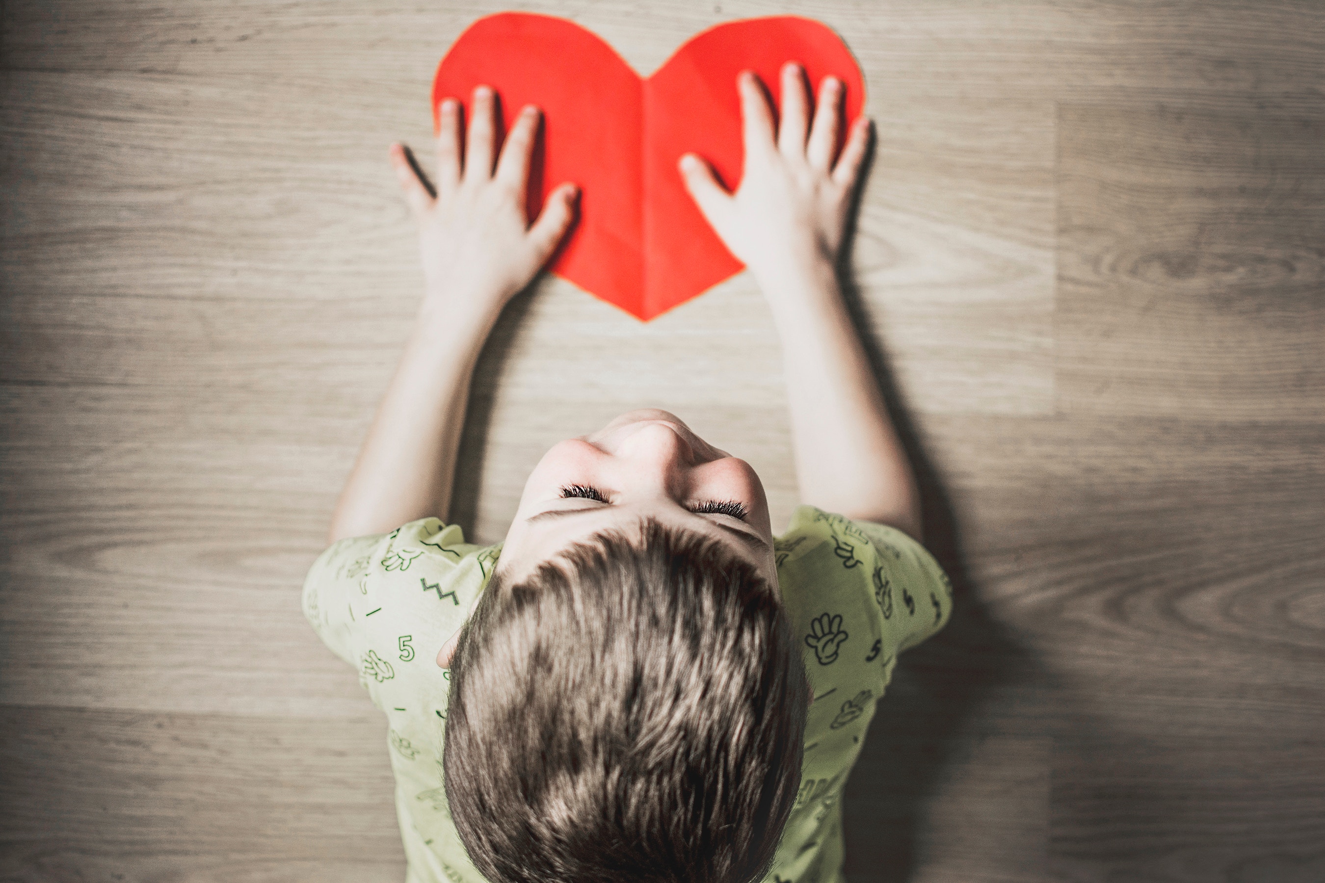 Boy holding a red heart on a wooden floor HD Wallpaper