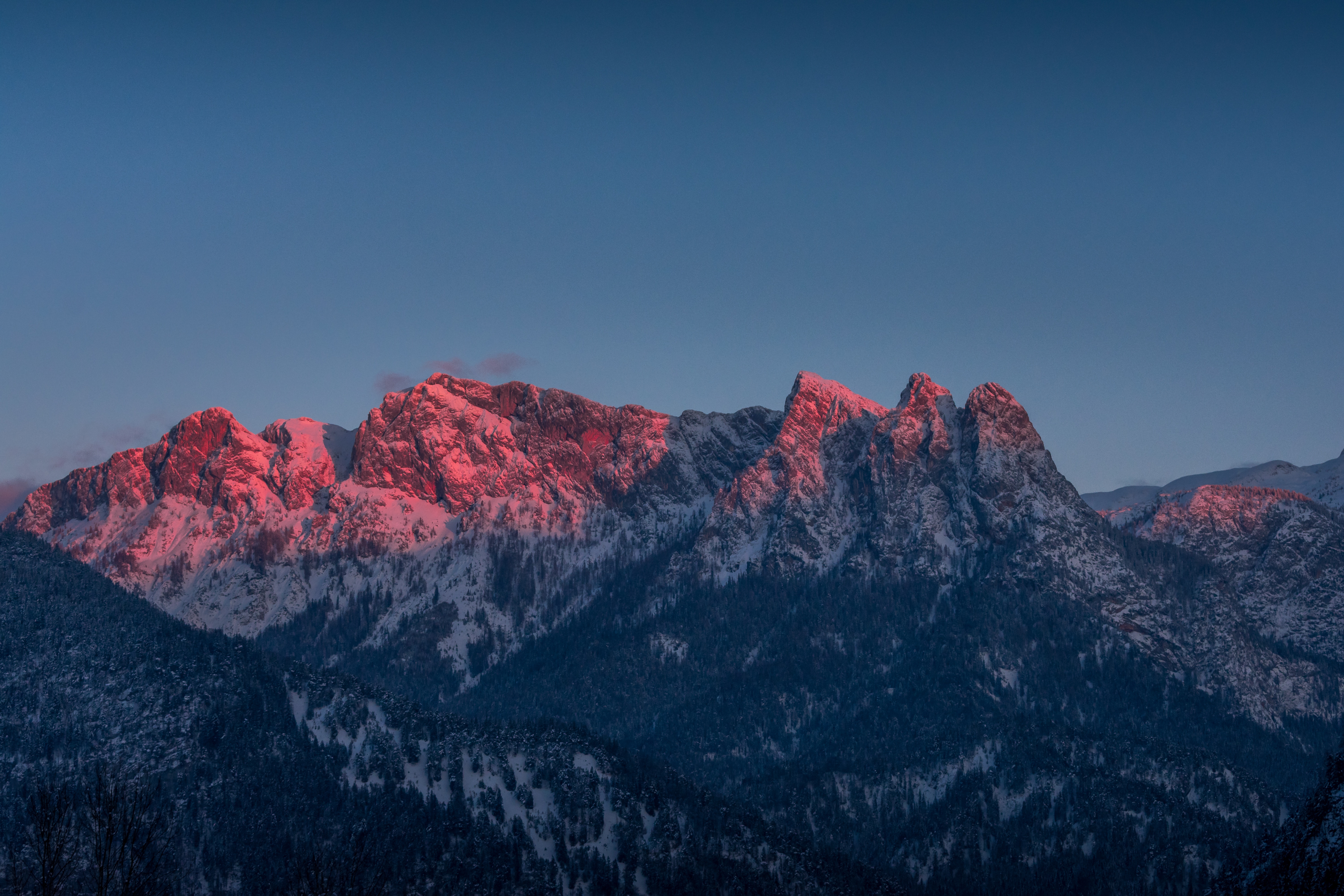 Pink-lit mountain range in winter at sunrise HD Wallpaper