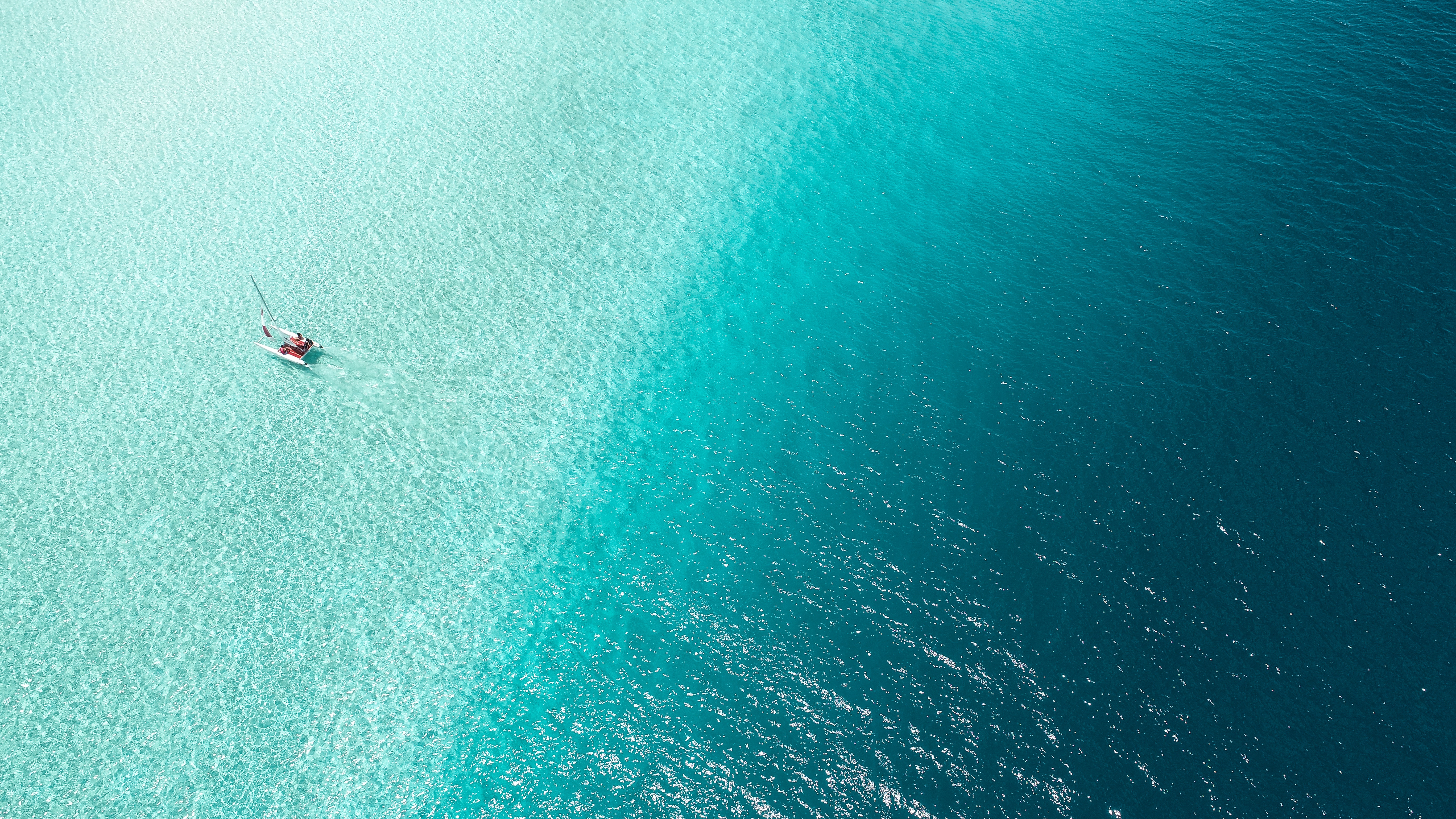 Aerial view of a sailboat on turquoise water HD Wallpaper