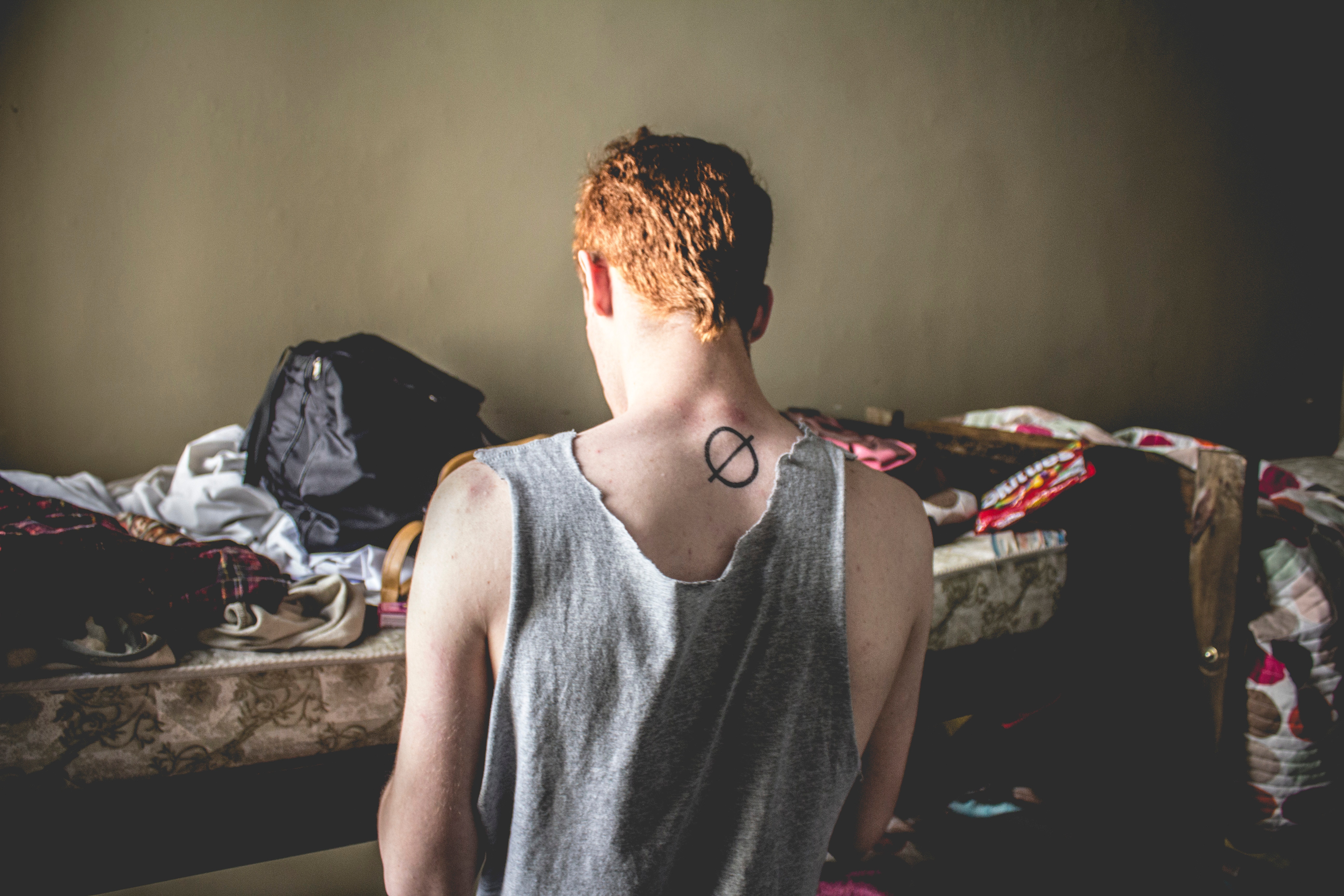 Man with tattoo on back in messy room HD Wallpaper