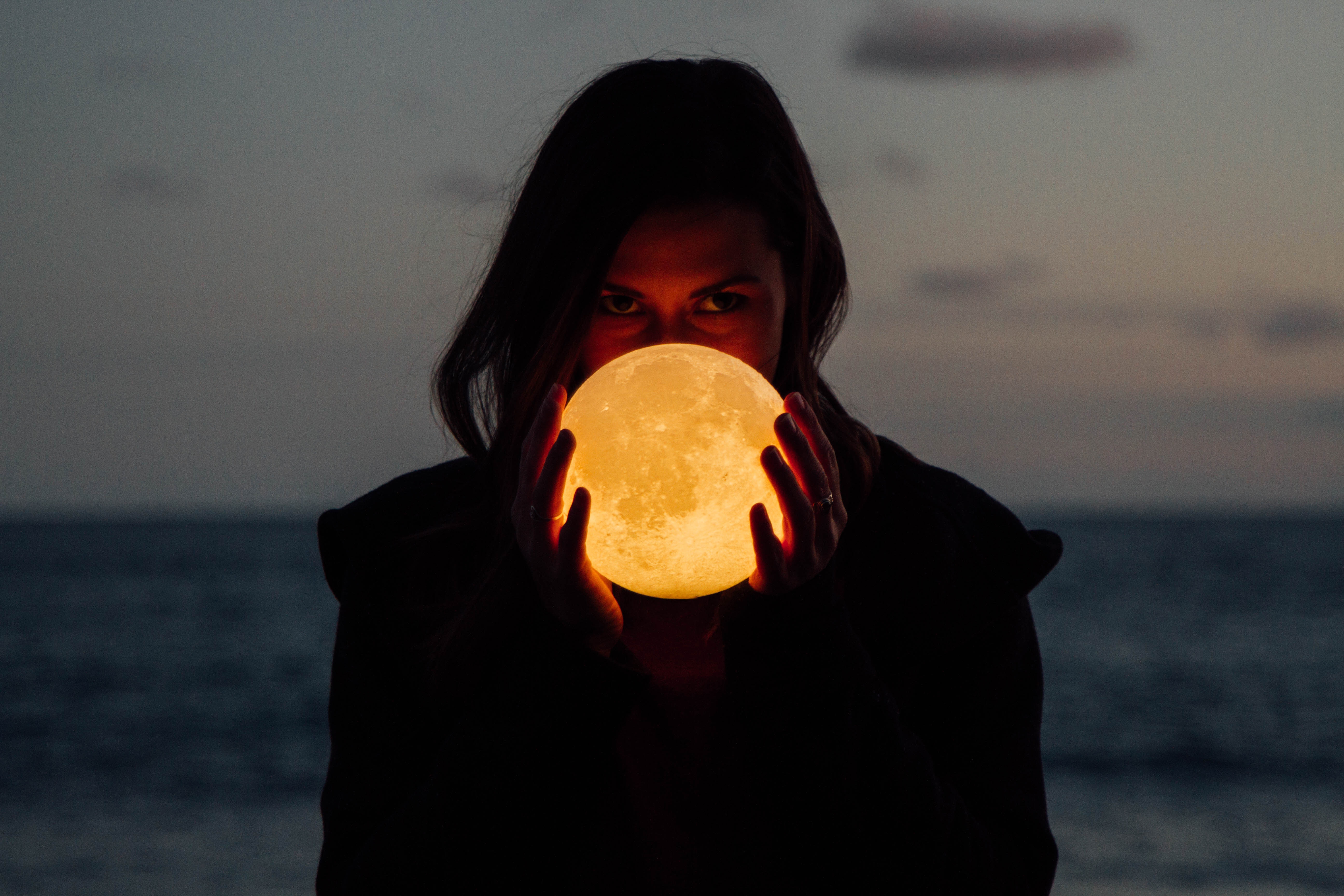 Woman holding a glowing moon lamp at dusk HD Wallpaper