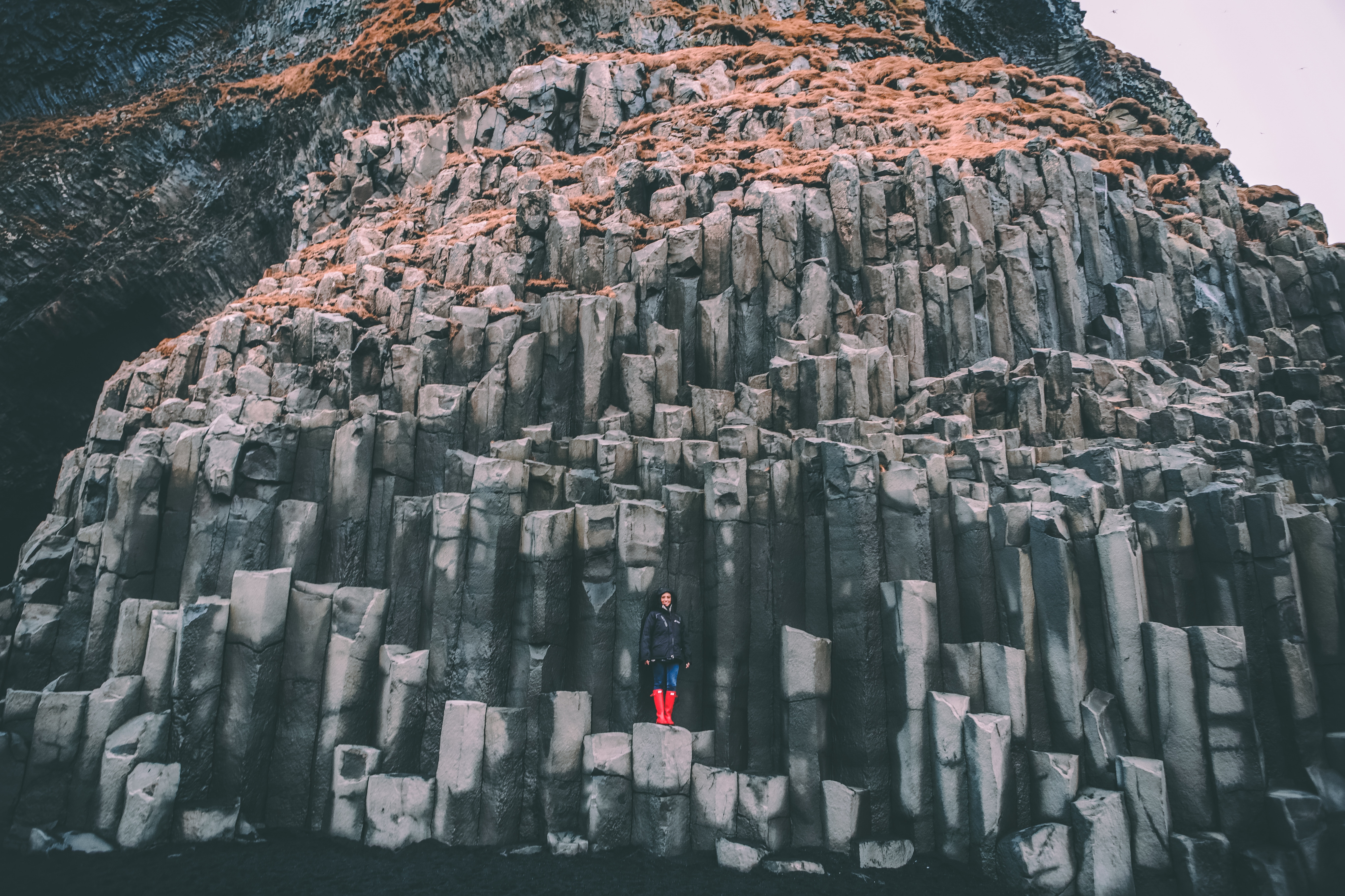 Person standing on basalt columns at Reynisfjara, Iceland HD Wallpaper