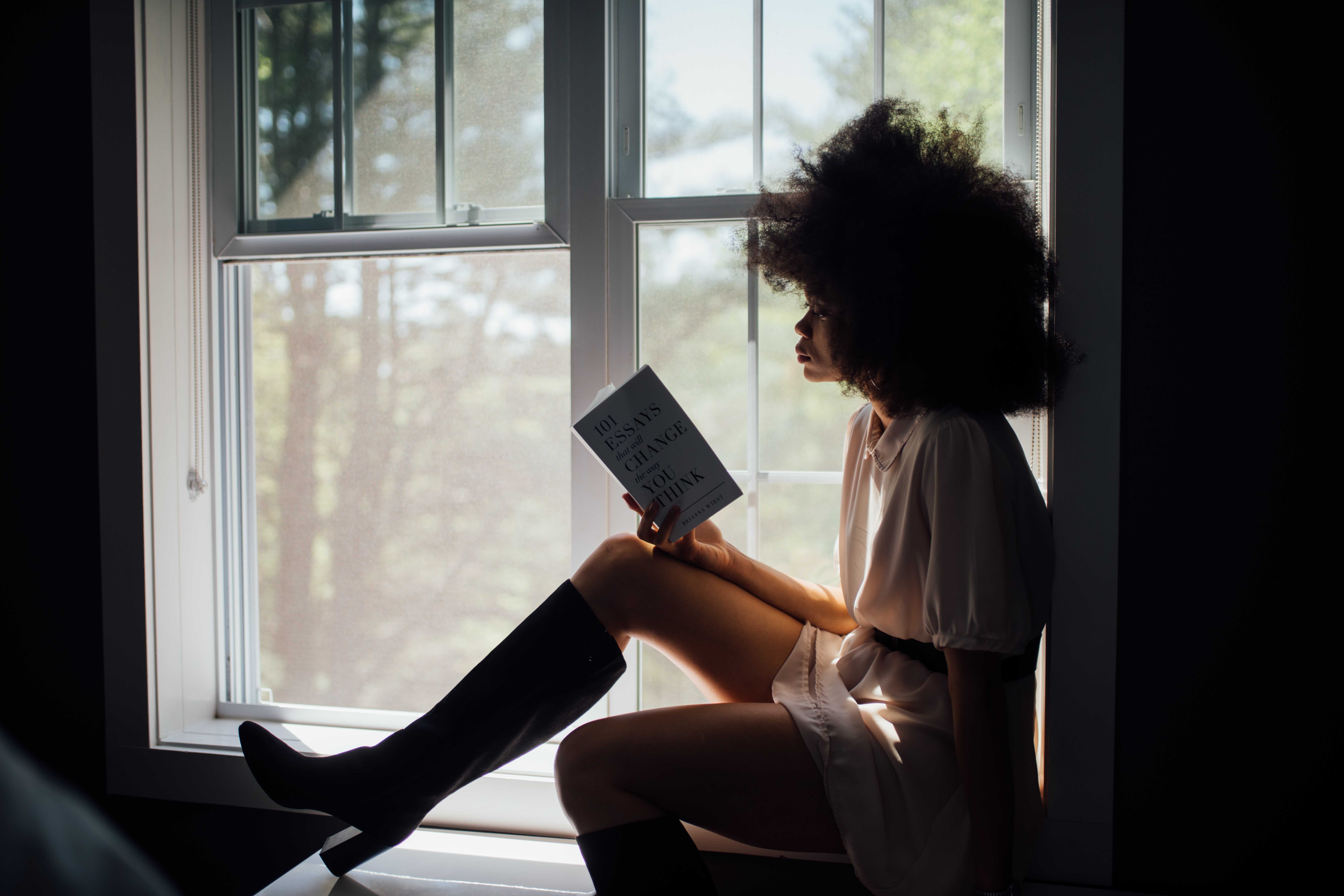 Woman with afro reading a book by the window HD Wallpaper