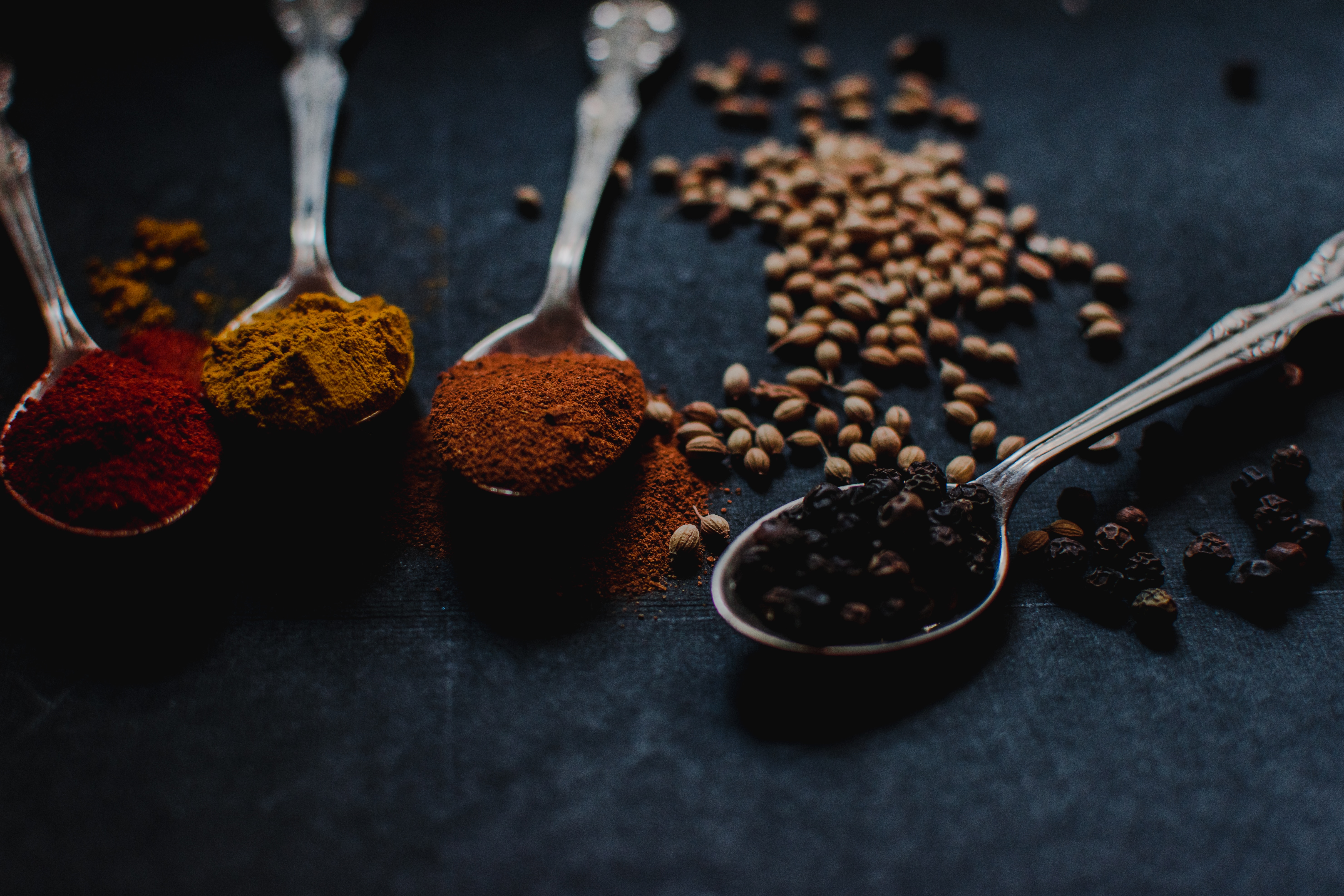 Four spoons filled with colorful spices on a dark surface HD Wallpaper