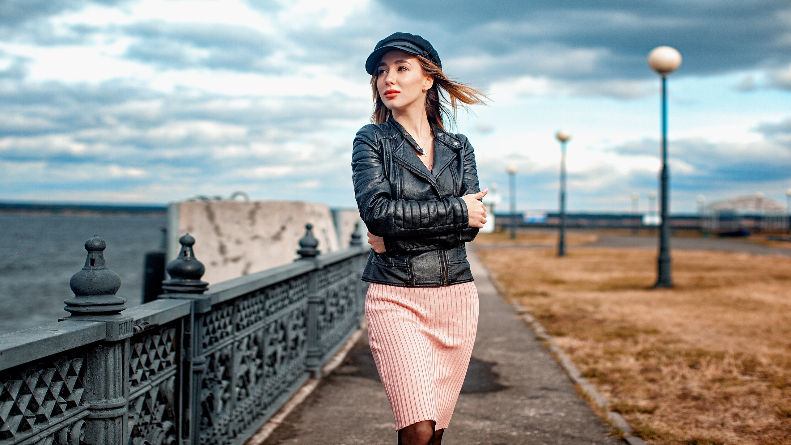Woman in leather jacket and cap walking by the water HD Wallpaper