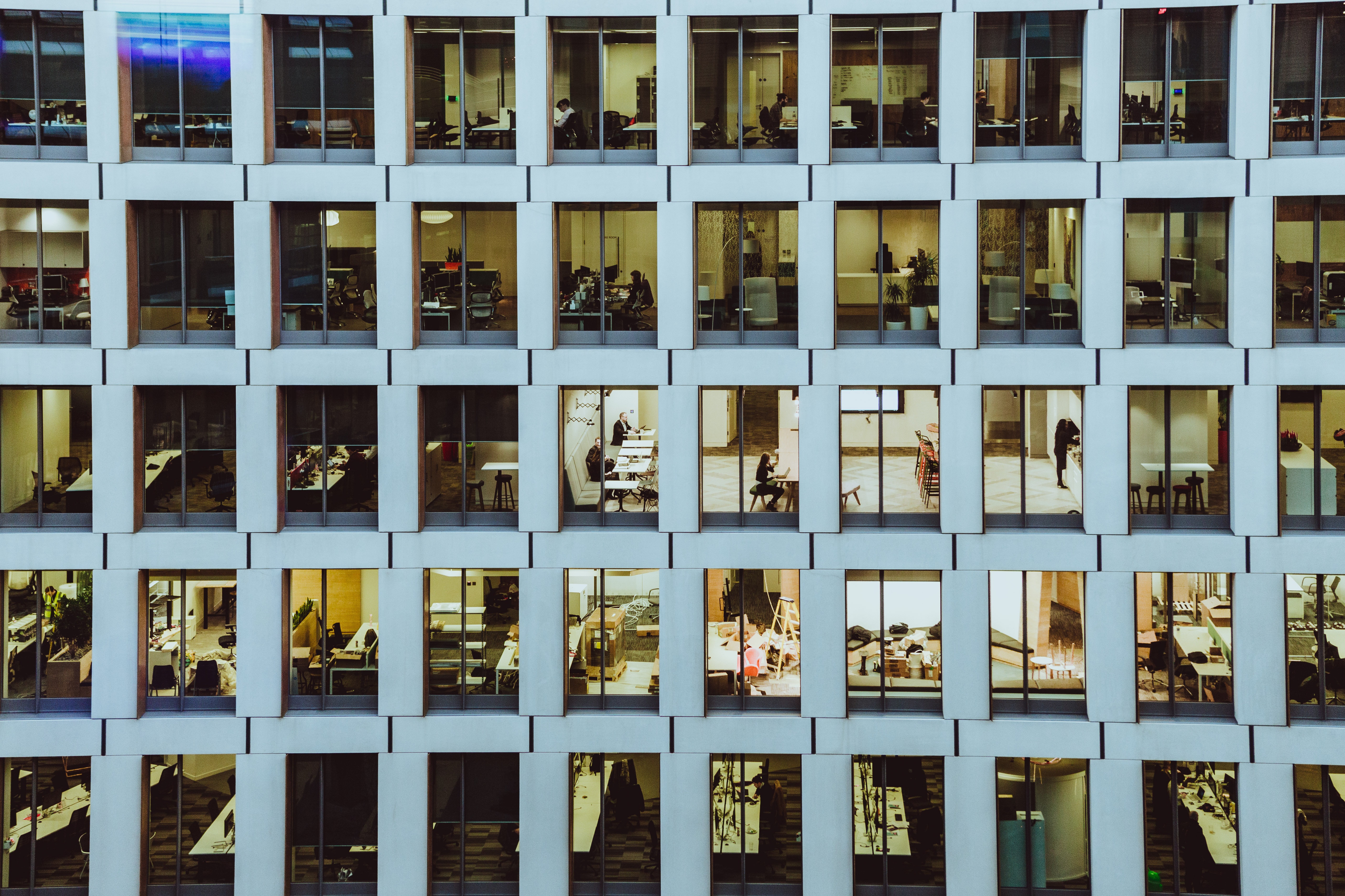 Office building windows with people working inside HD Wallpaper