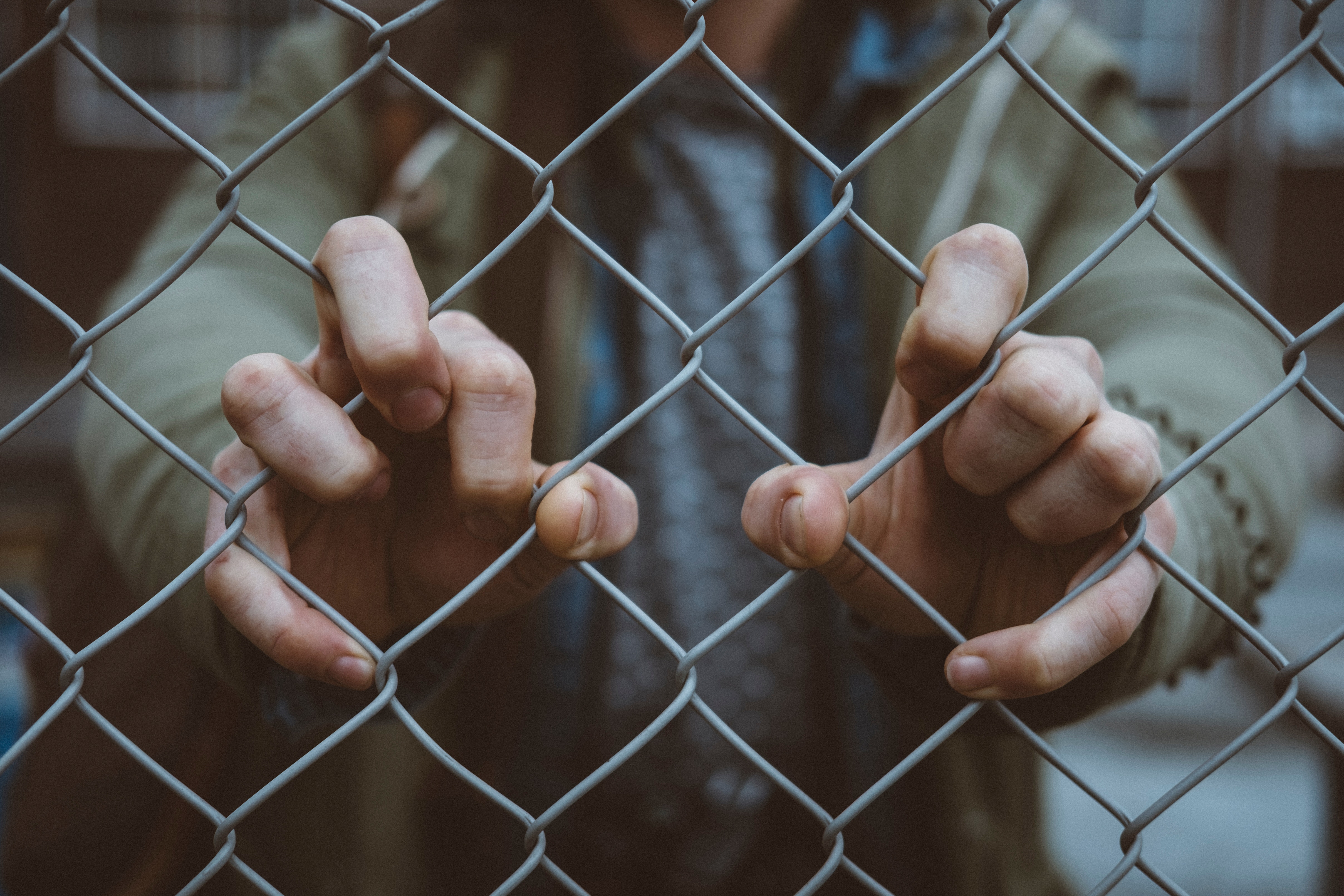 Person gripping a chain-link fence HD Wallpaper