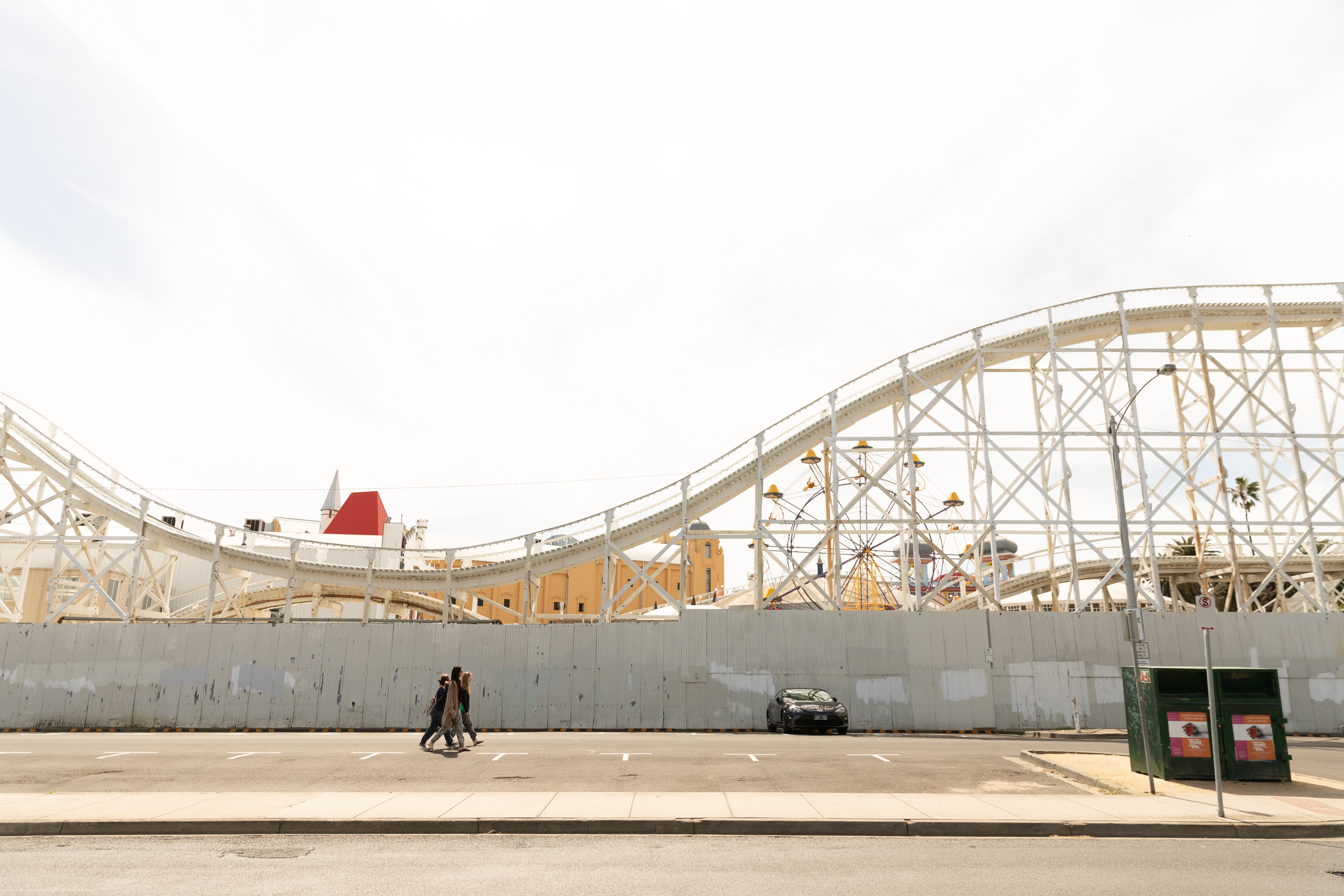 Roller coaster at amusement park with people walking HD Wallpaper