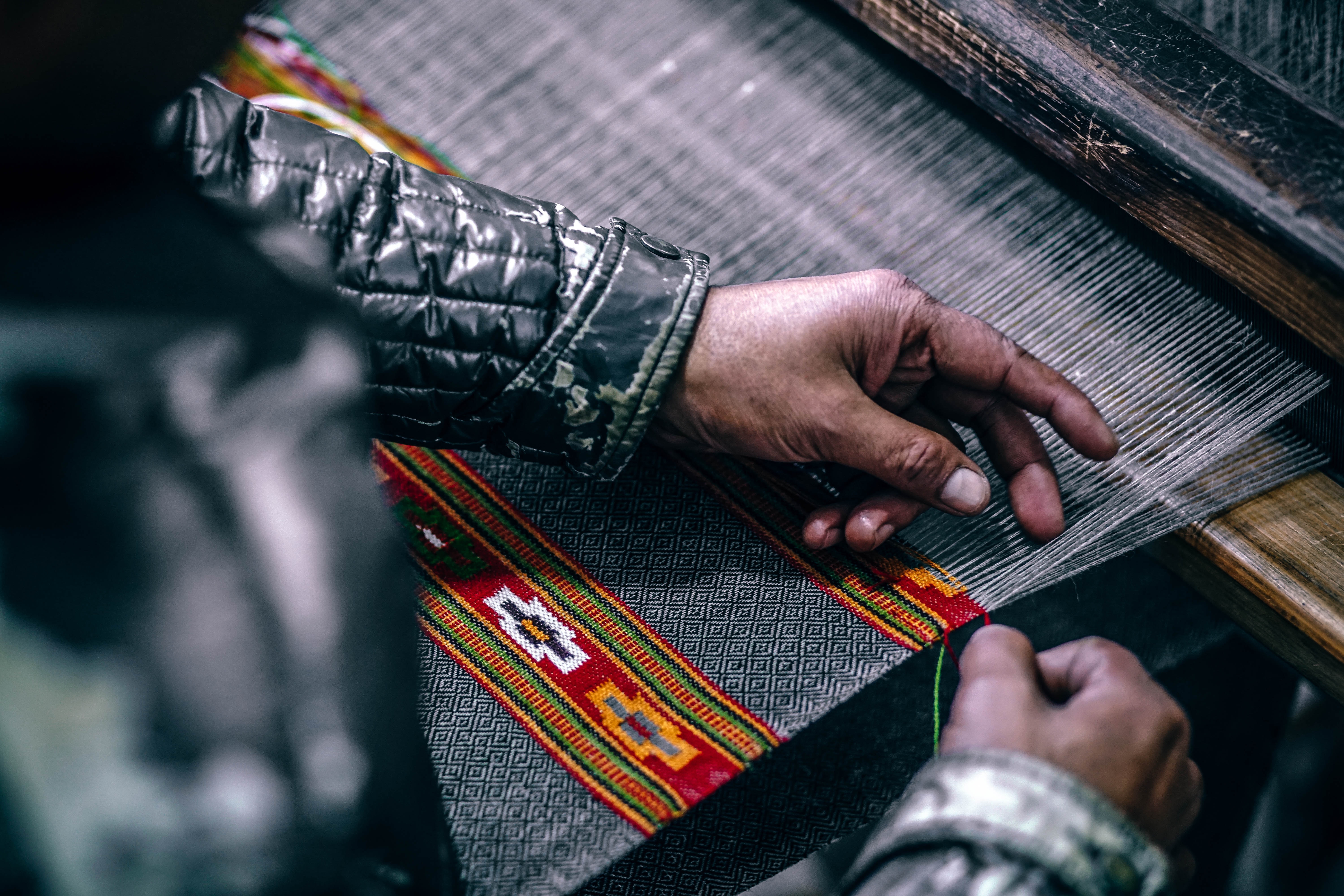 Hands weaving colorful fabric on a loom HD Wallpaper