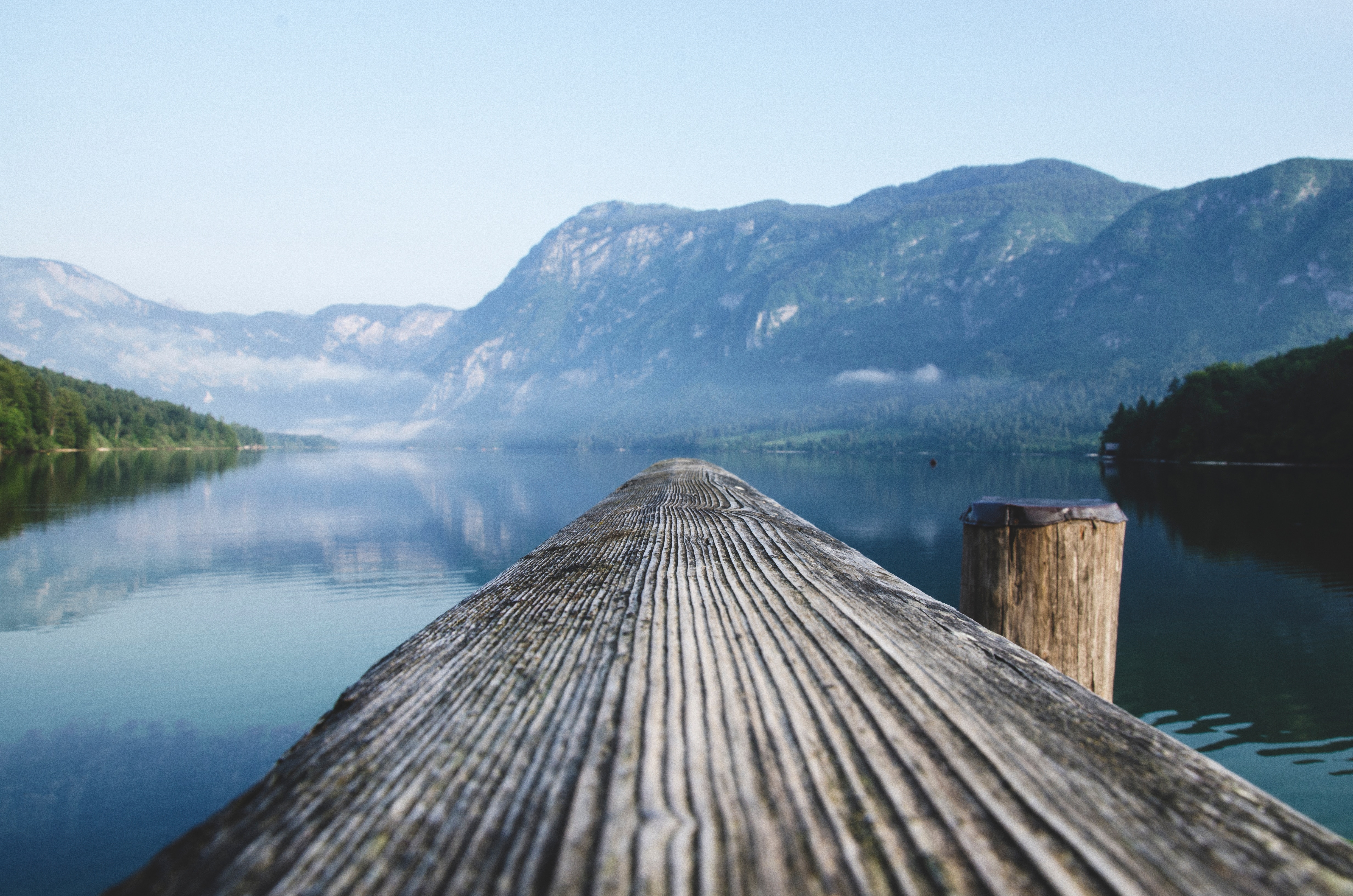 Wooden pier on a calm lake with mountains HD Wallpaper