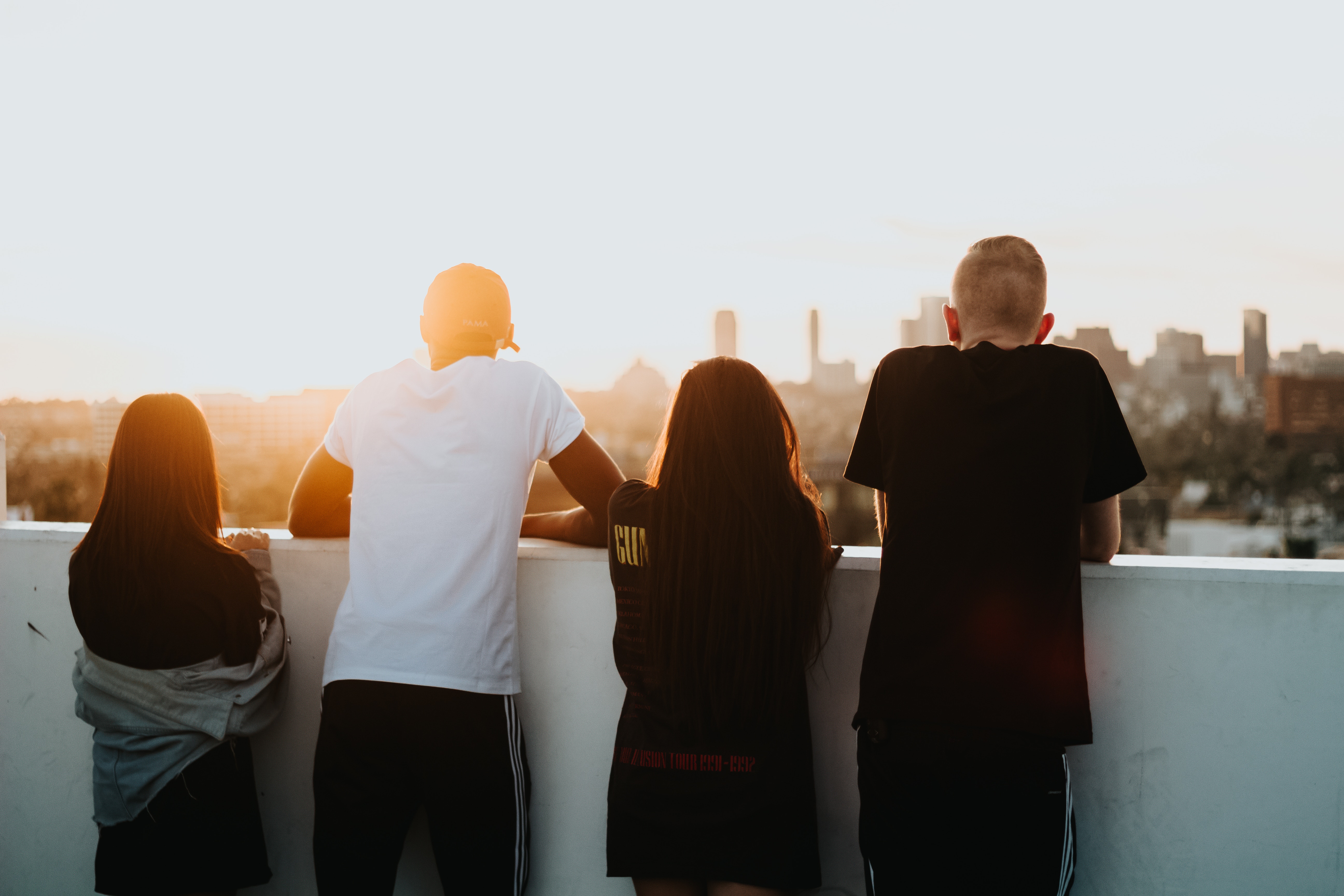 Four friends watching the sunset over a city skyline HD Wallpaper