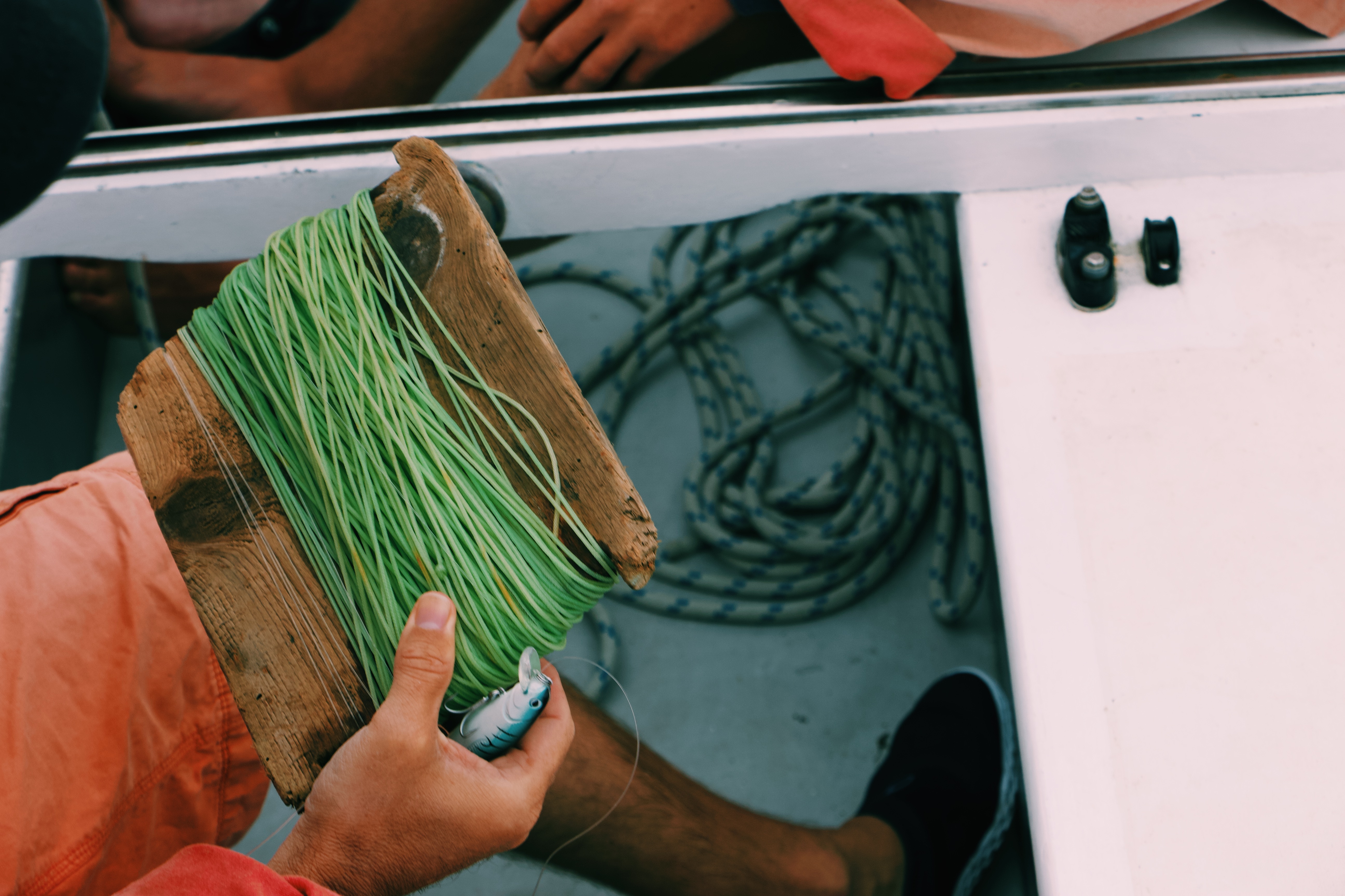 Person holding fishing line and lure on a boat HD Wallpaper