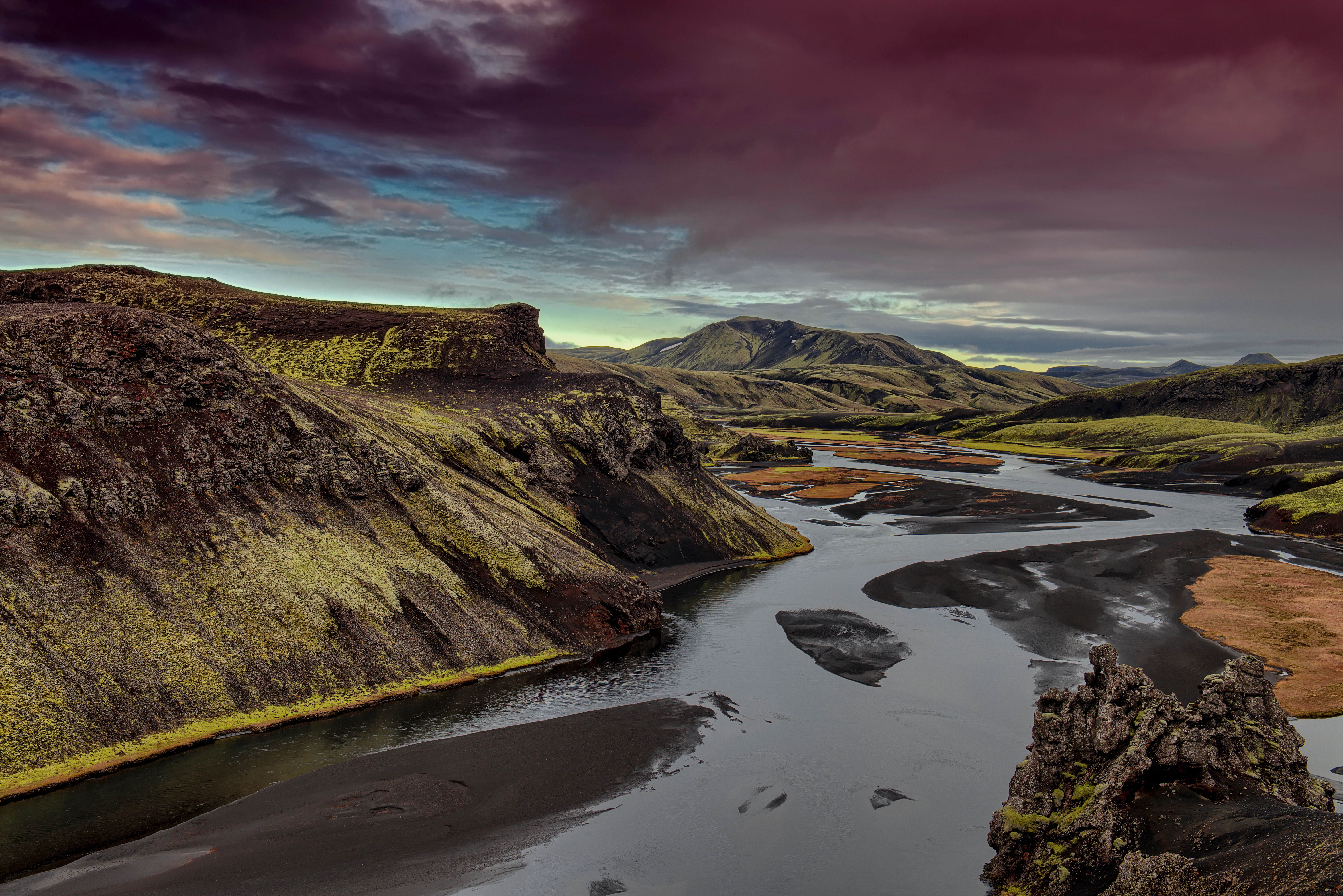 River flowing through Icelandic highlands under dramatic sky HD Wallpaper