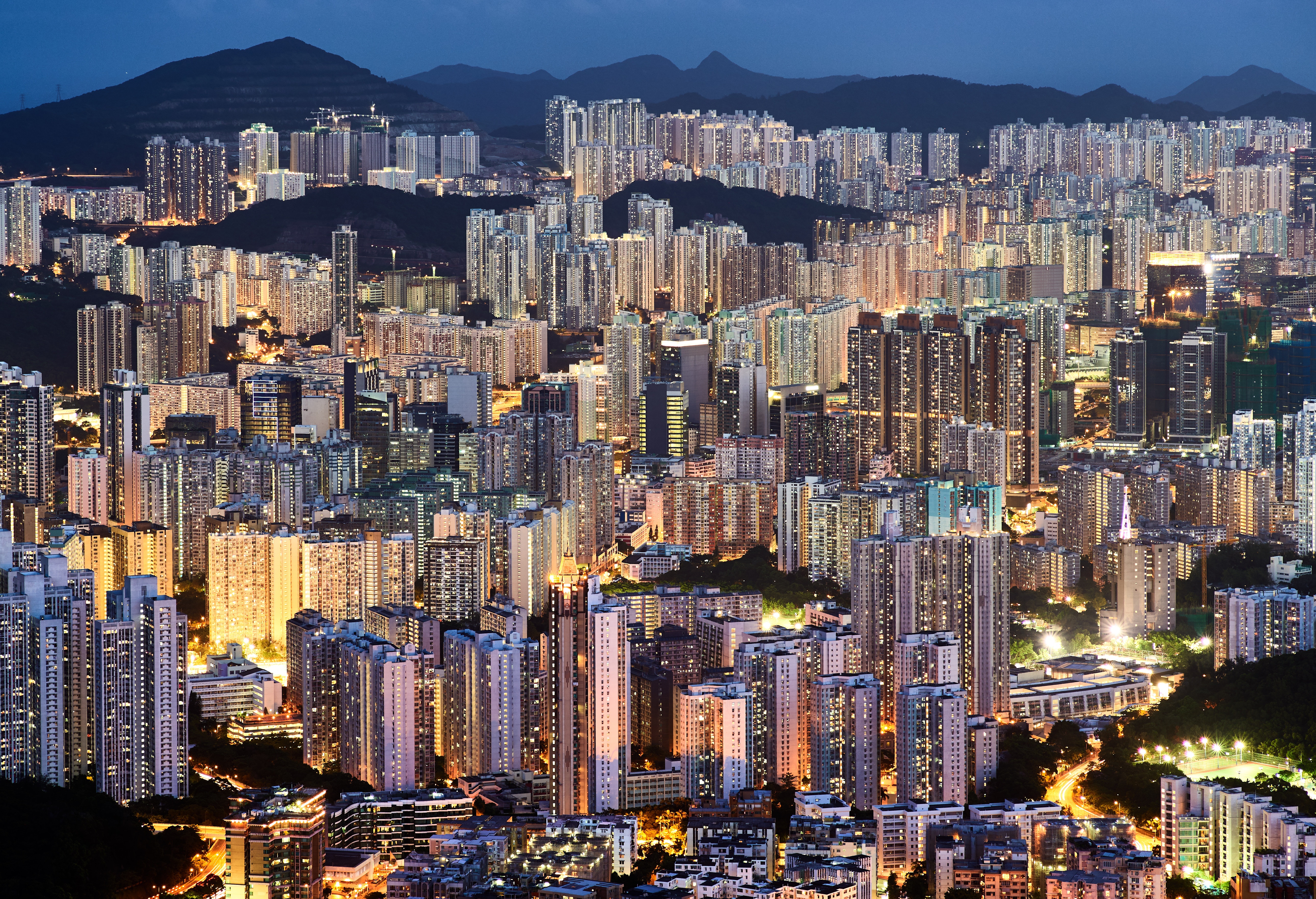 Hong Kong cityscape at night with dense buildings and hills HD Wallpaper