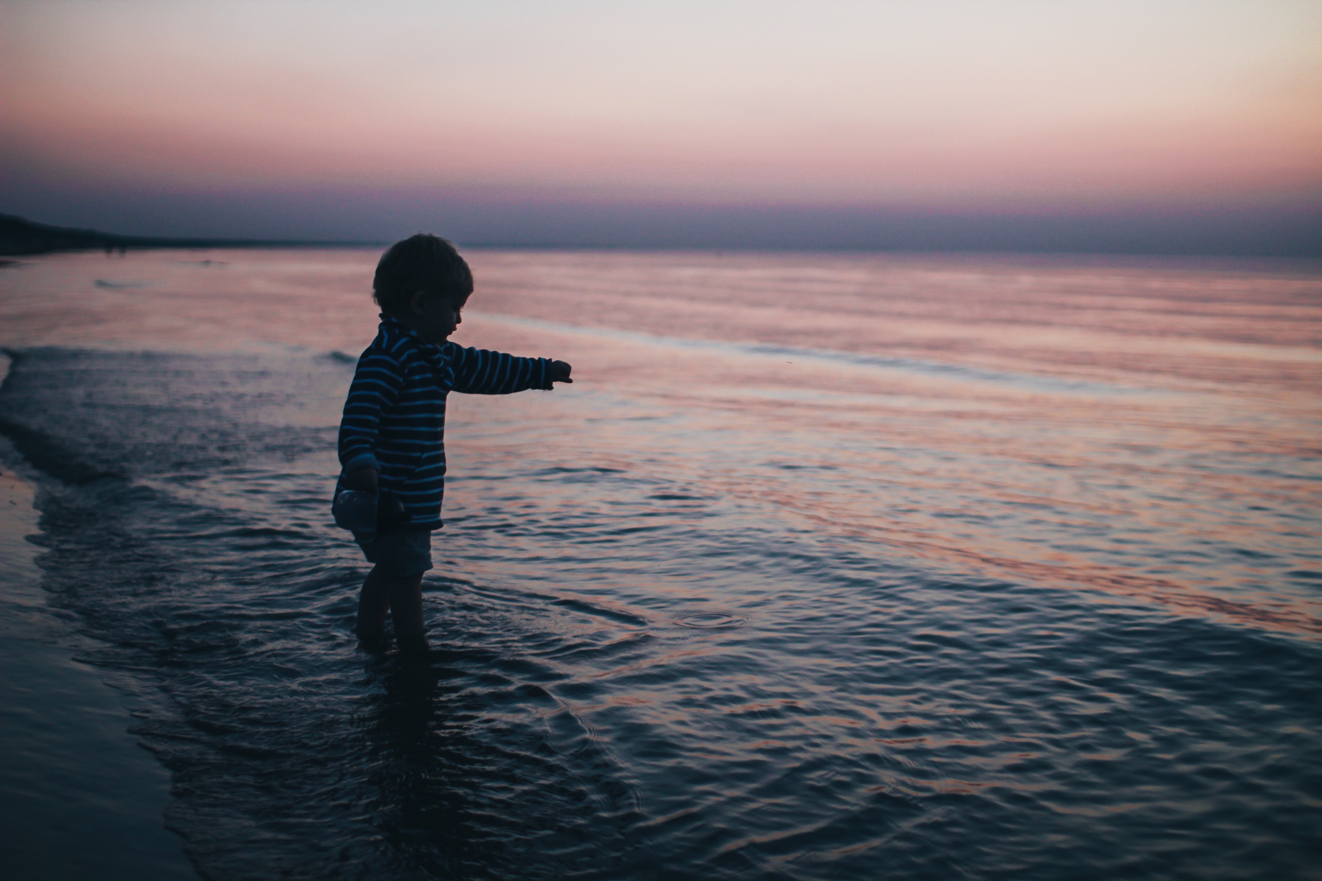Child playing at the shoreline during sunset HD Wallpaper
