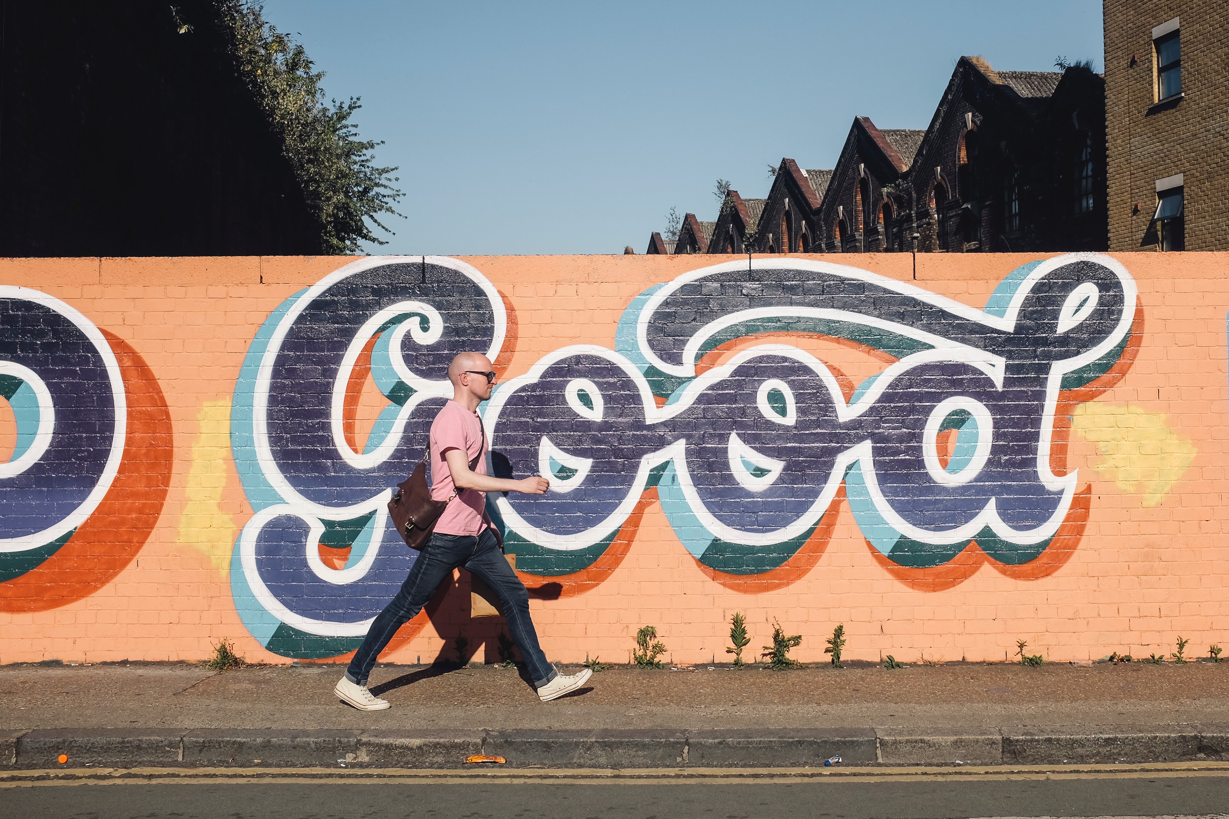 Man walks past graffiti art on a brick wall HD Wallpaper