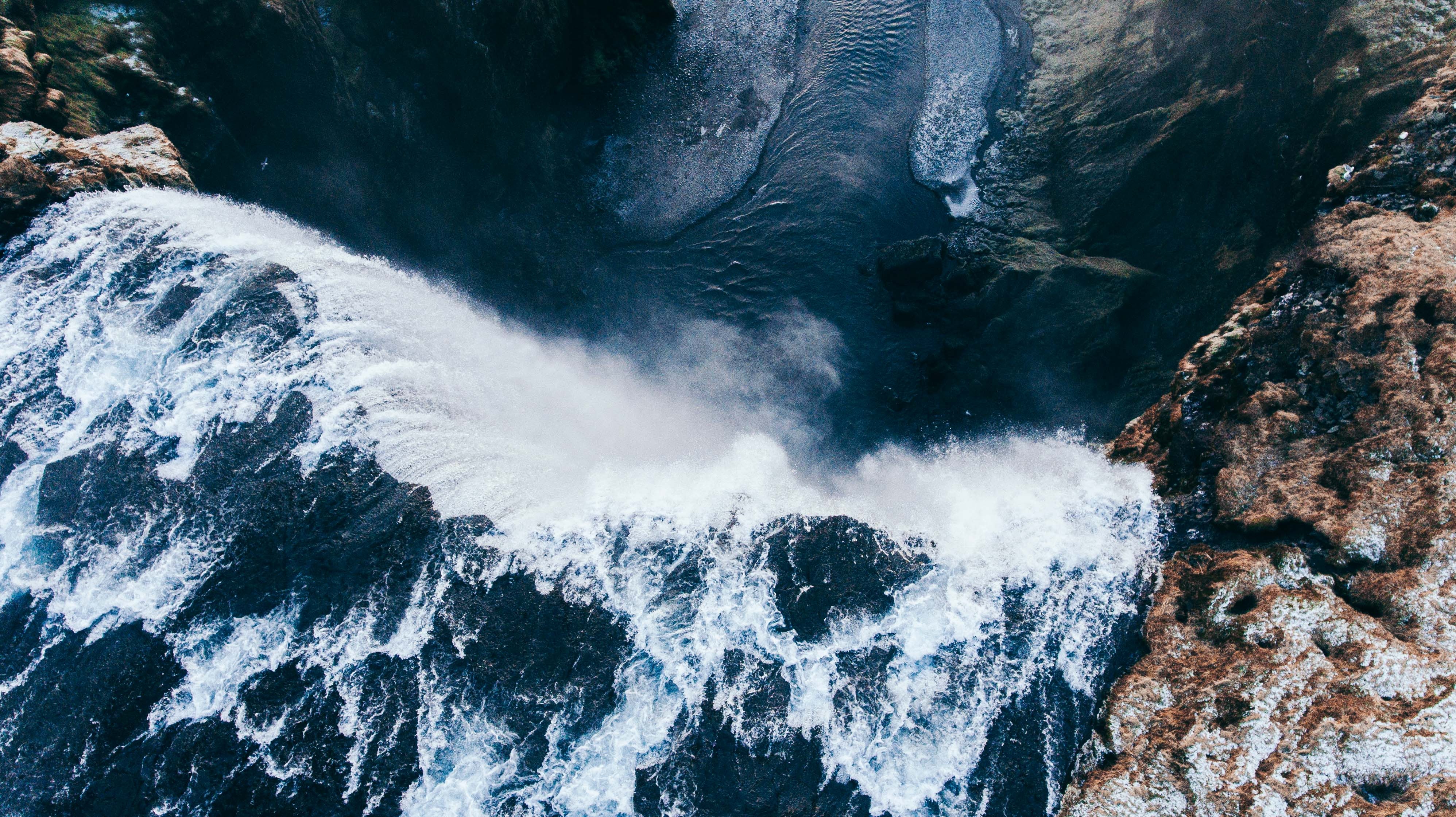 Aerial view of a powerful waterfall gushing over rocks HD Wallpaper