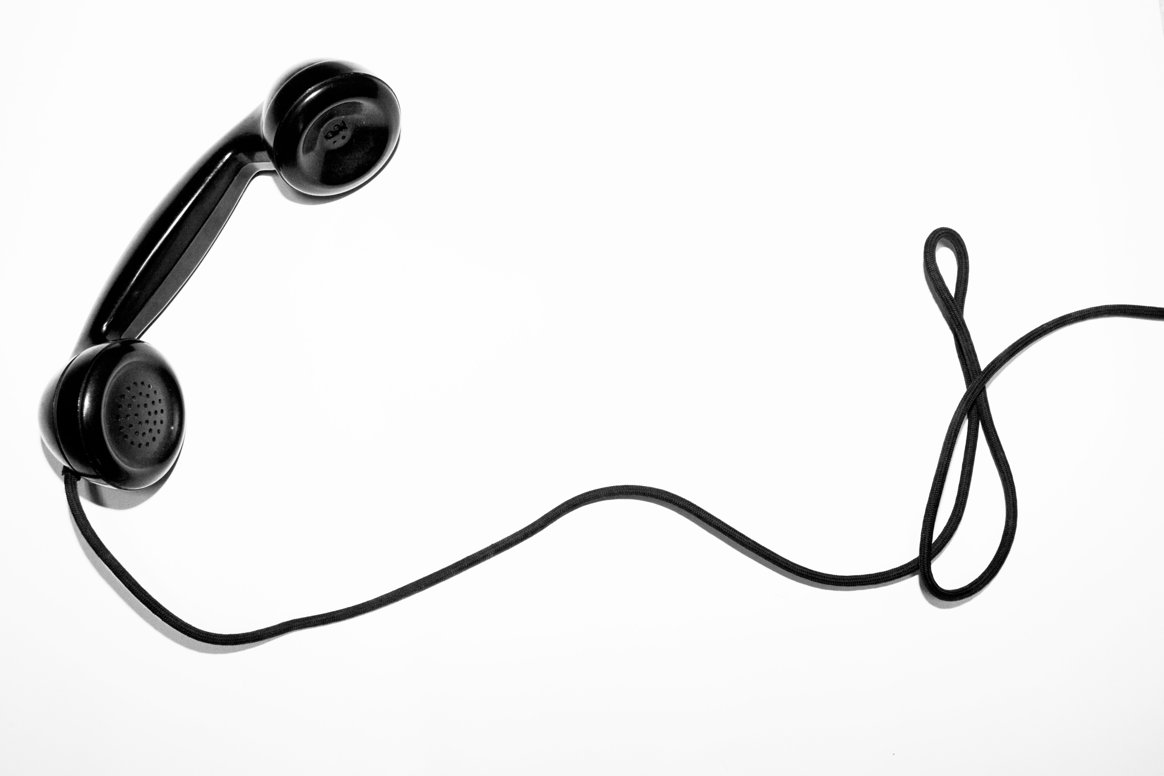 Black telephone handset with coiled cord on white background HD Wallpaper