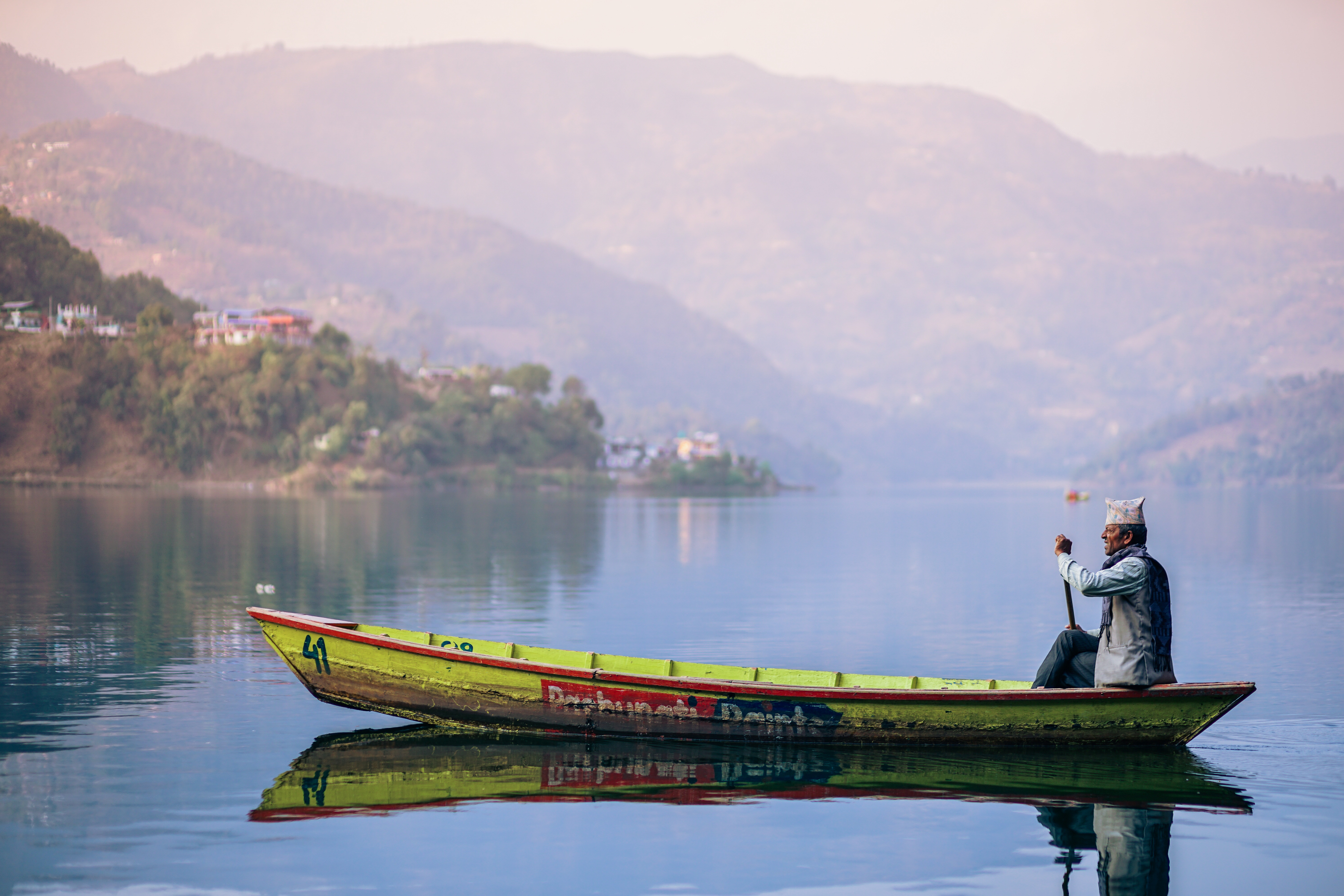 Man rowing a boat on a lake with mountains HD Wallpaper