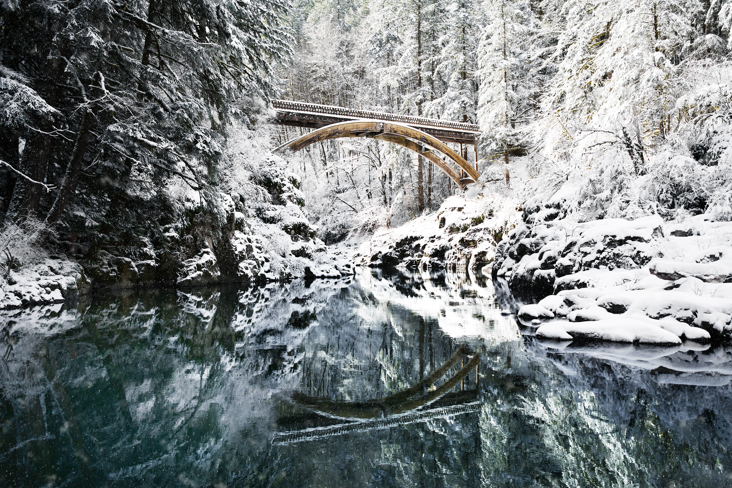 Arch bridge over a river in a snowy forest HD Wallpaper