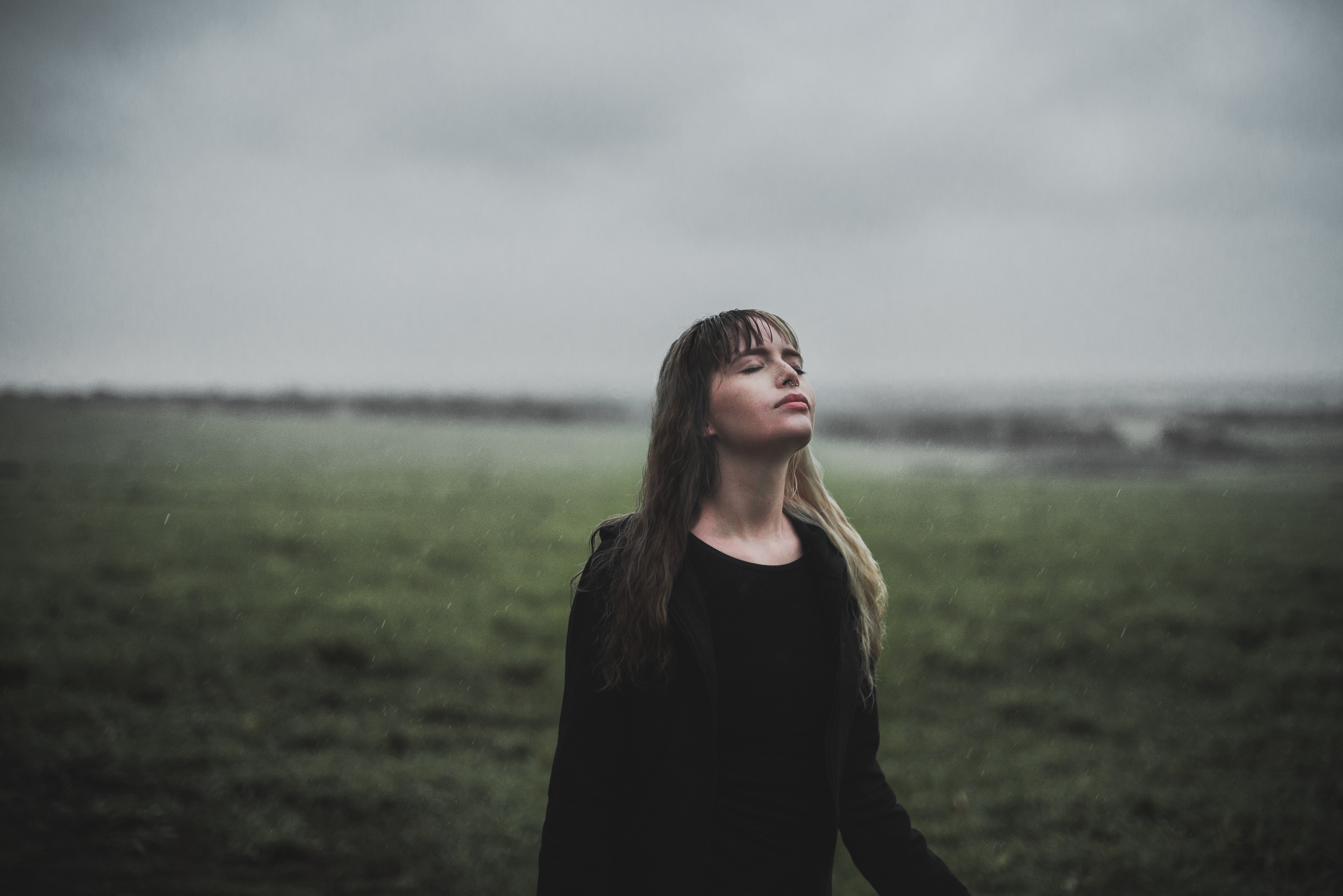 Woman in black sweater standing in a rainy field HD Wallpaper