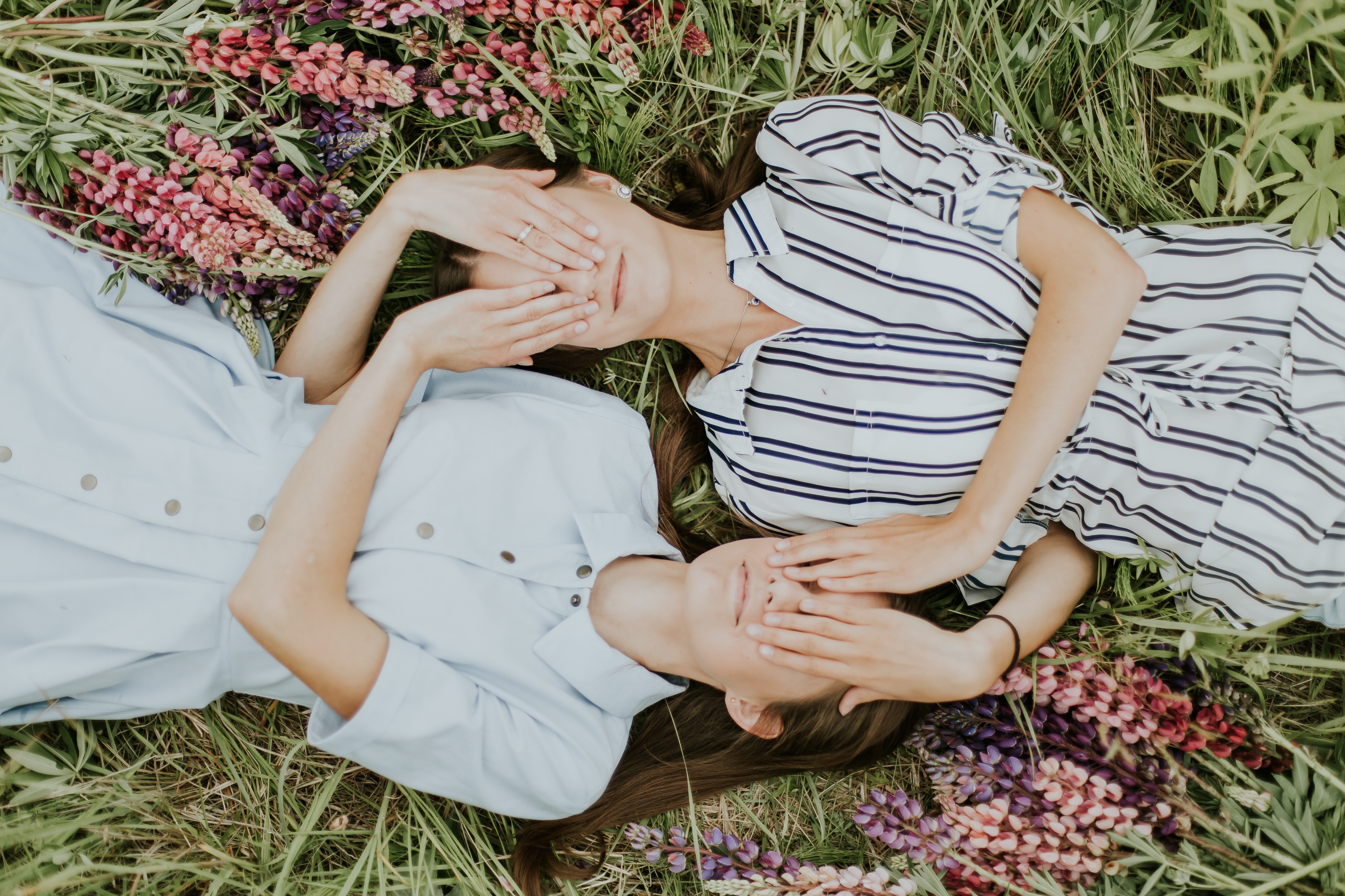 Two women lying in grass with flowers HD Wallpaper