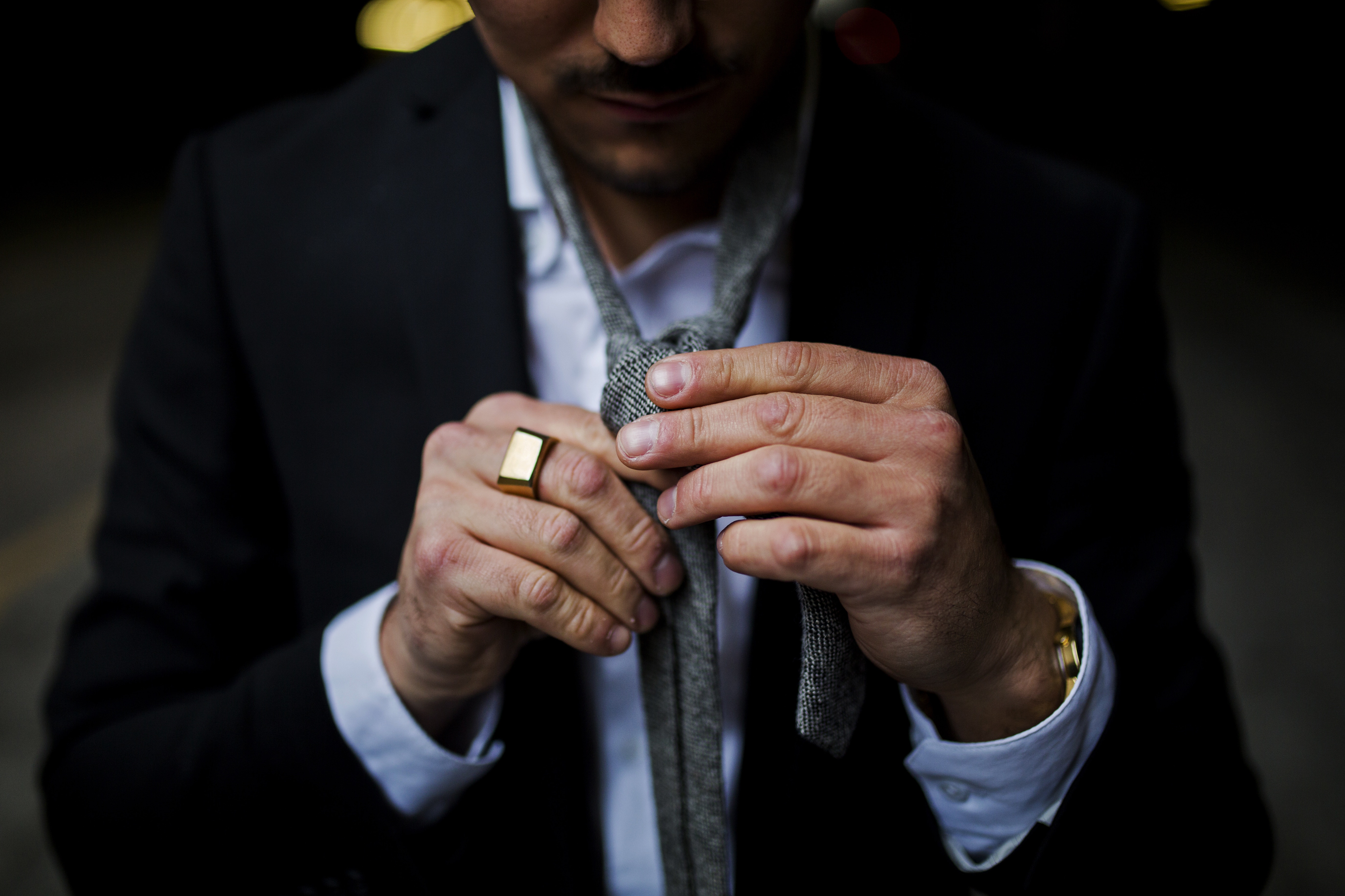 Man in suit tying a tie, close-up HD Wallpaper